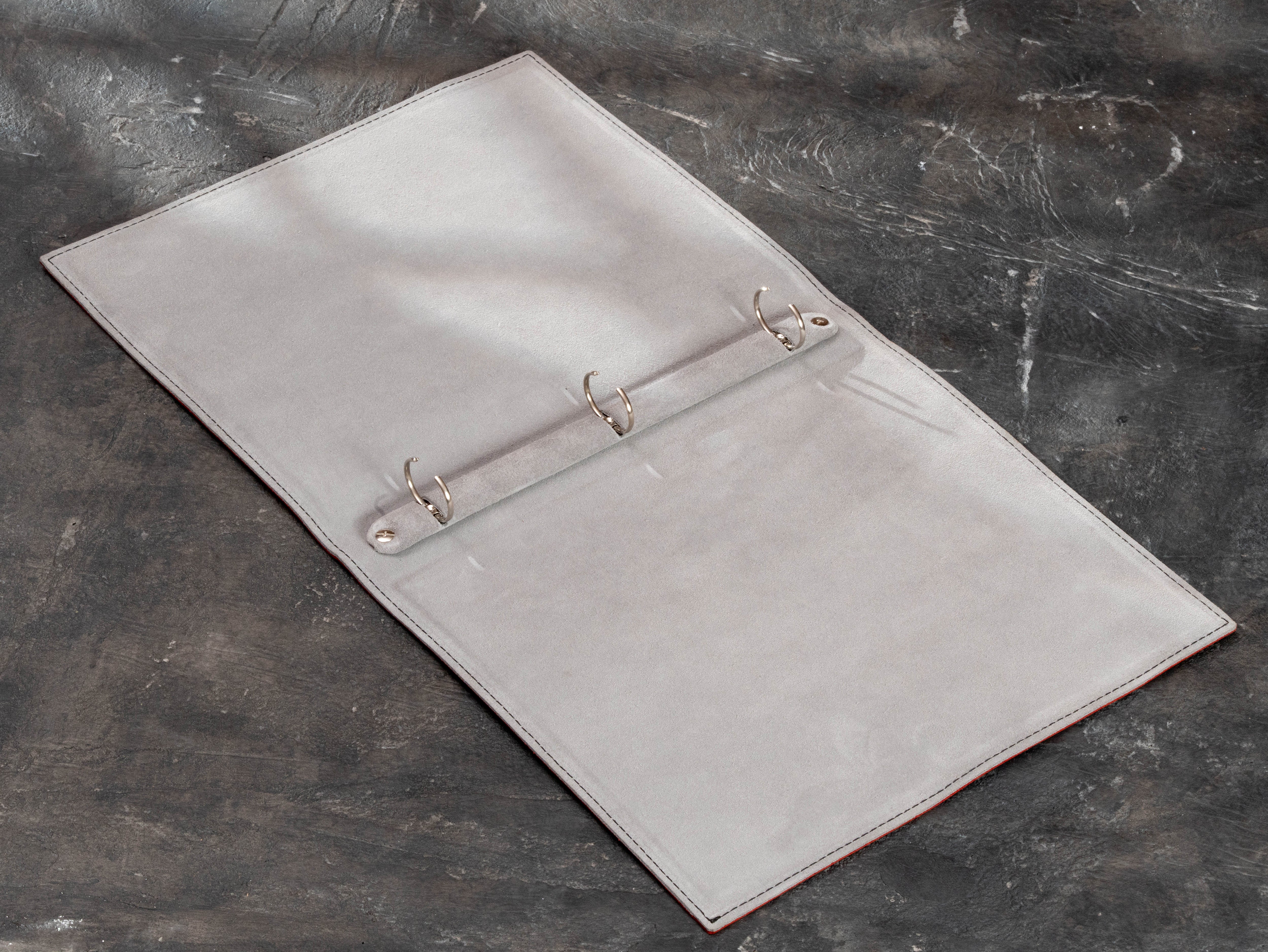 Light interior of custom leather sailing logbook binder with three rings raised for adding club records and archival pages.
