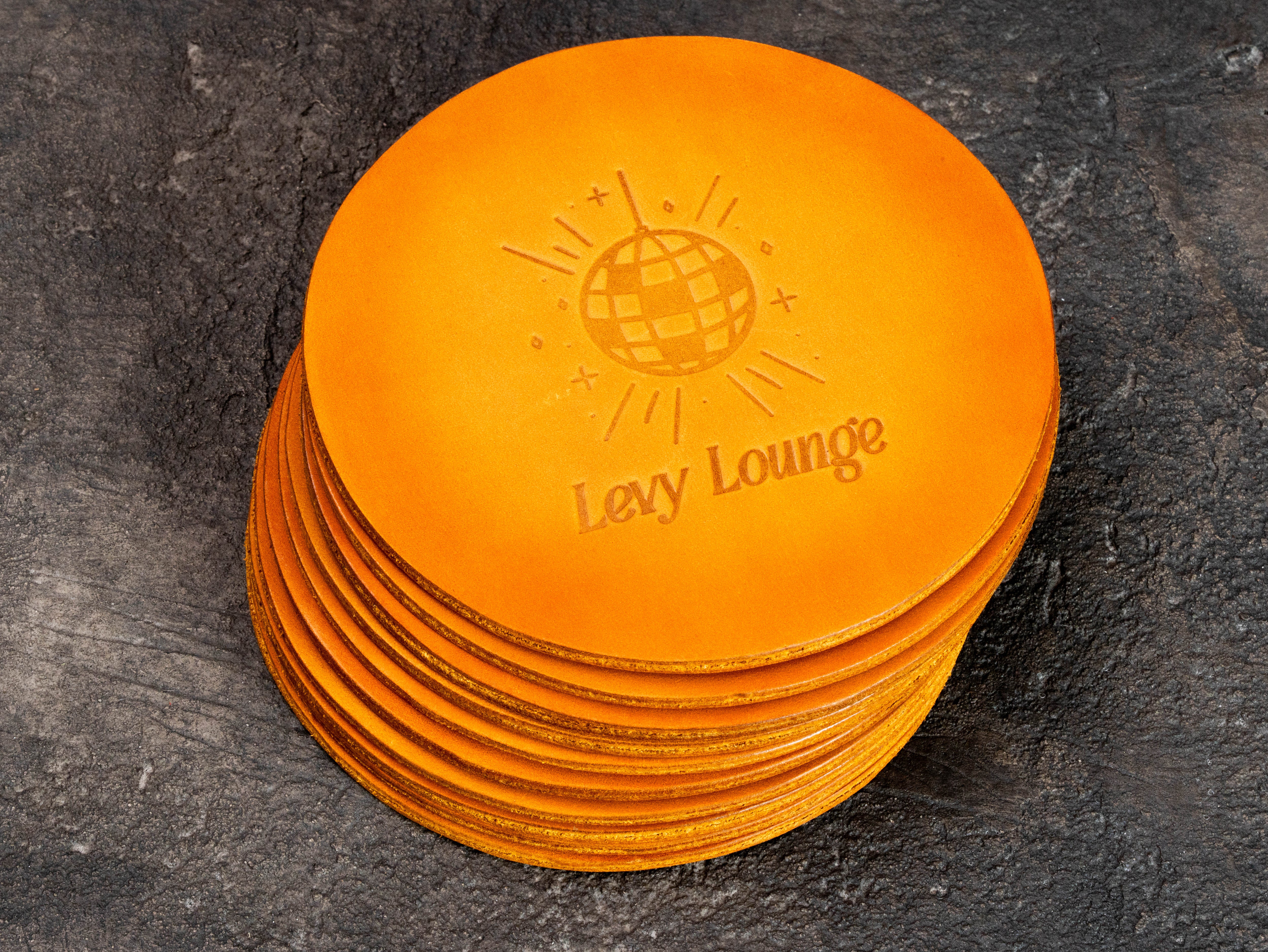Personalized round leather coasters set of 4 with double-sided custom embossing and hand-applied warm orange color