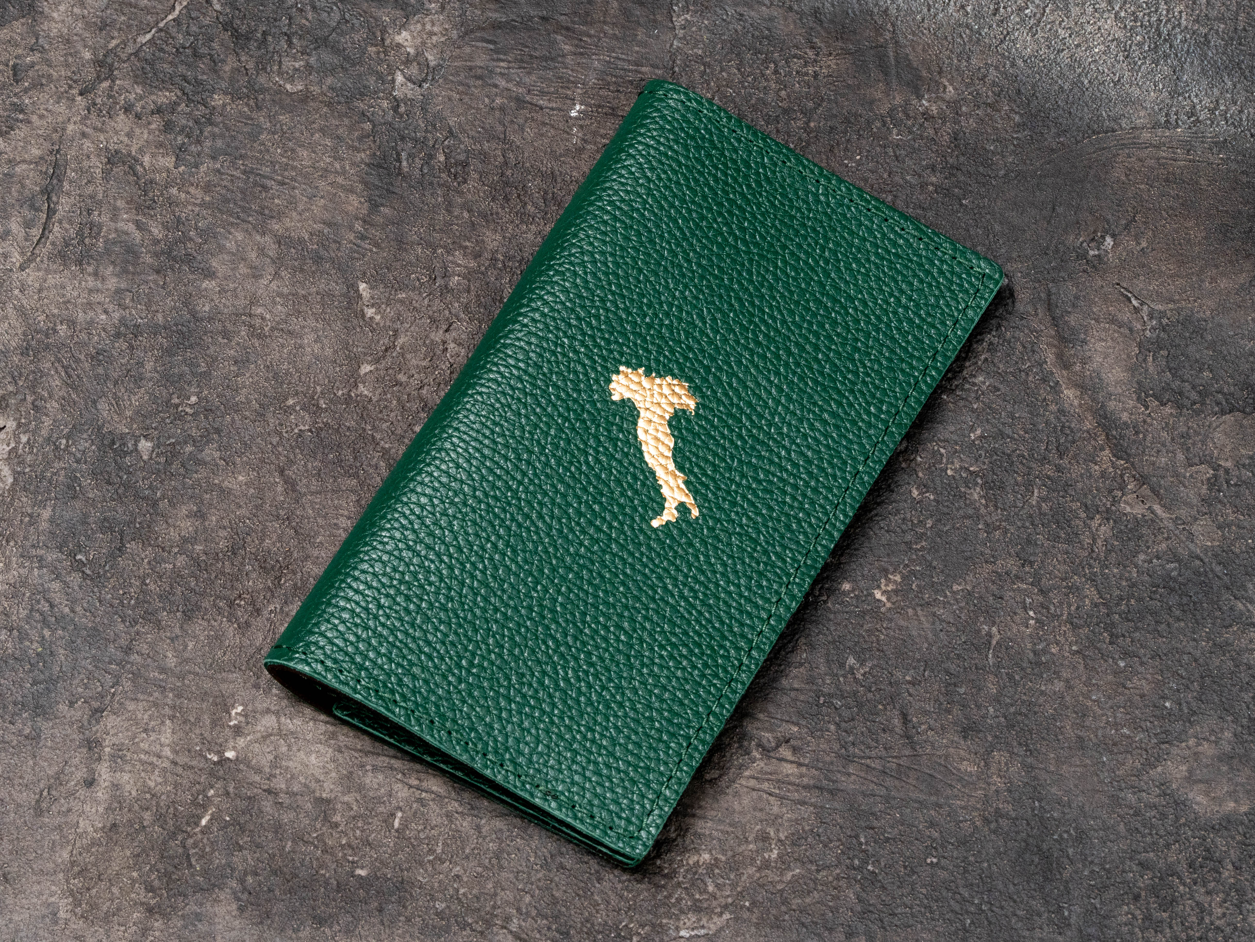 Closed green leather restaurant check presenter with gold foil logo on textured floater leather exterior