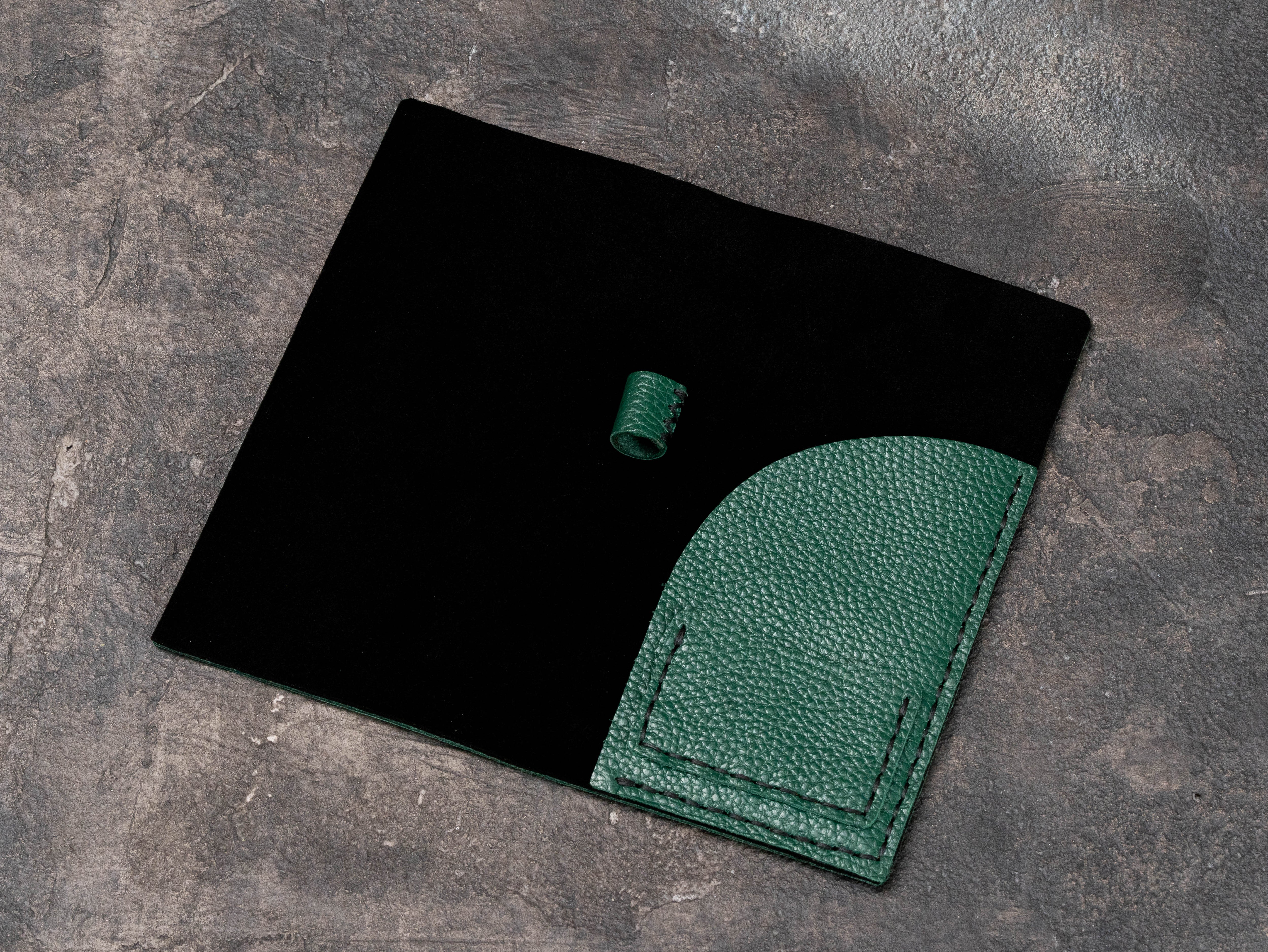 Empty open green leather restaurant check folder showing black suede interior, curved pocket and hand-sewn pen loop