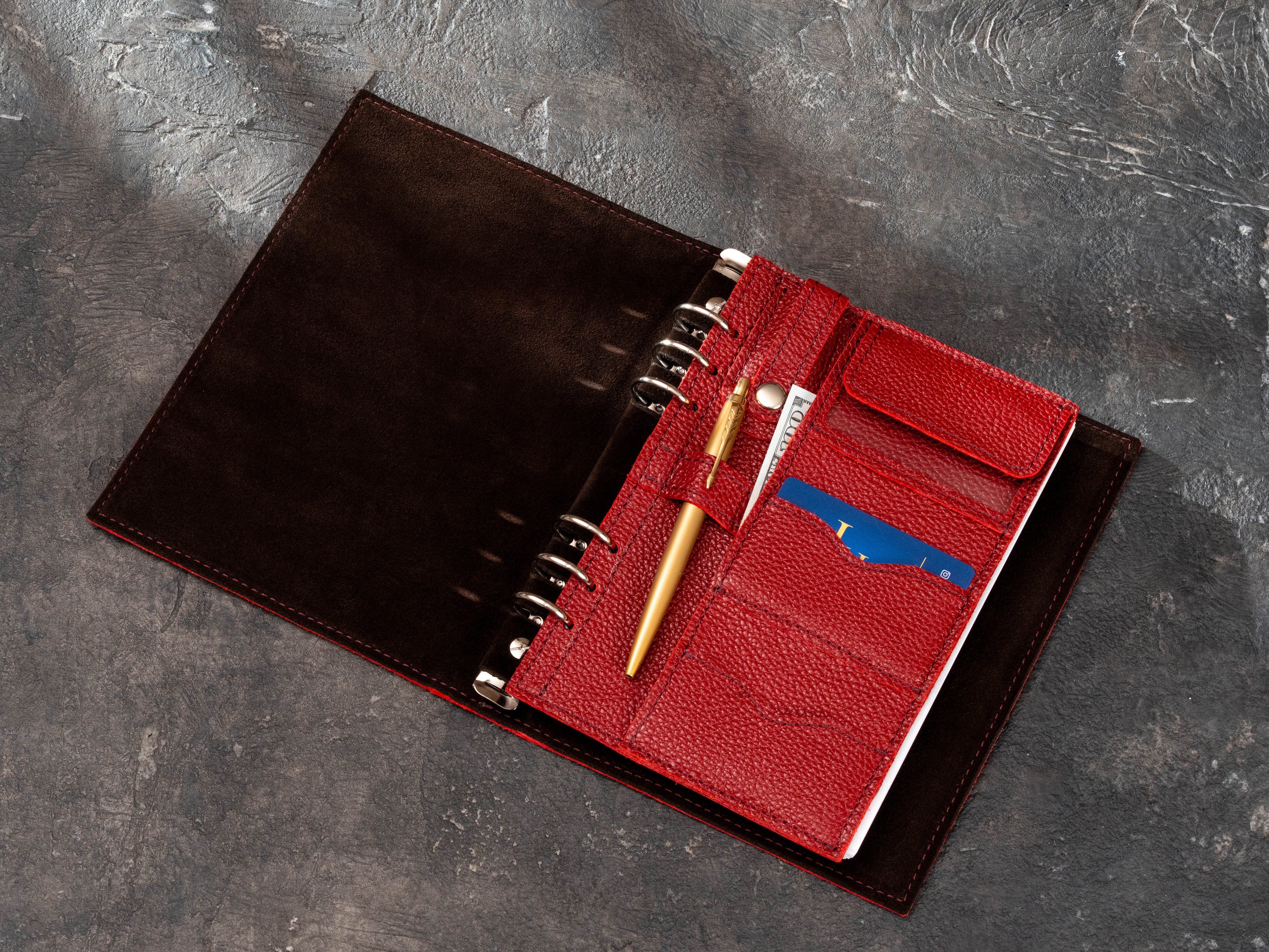 Open corporate ring binder notebook with removable red leather organizer insert, pen loop, card slots, cash pocket and flap compartment.
