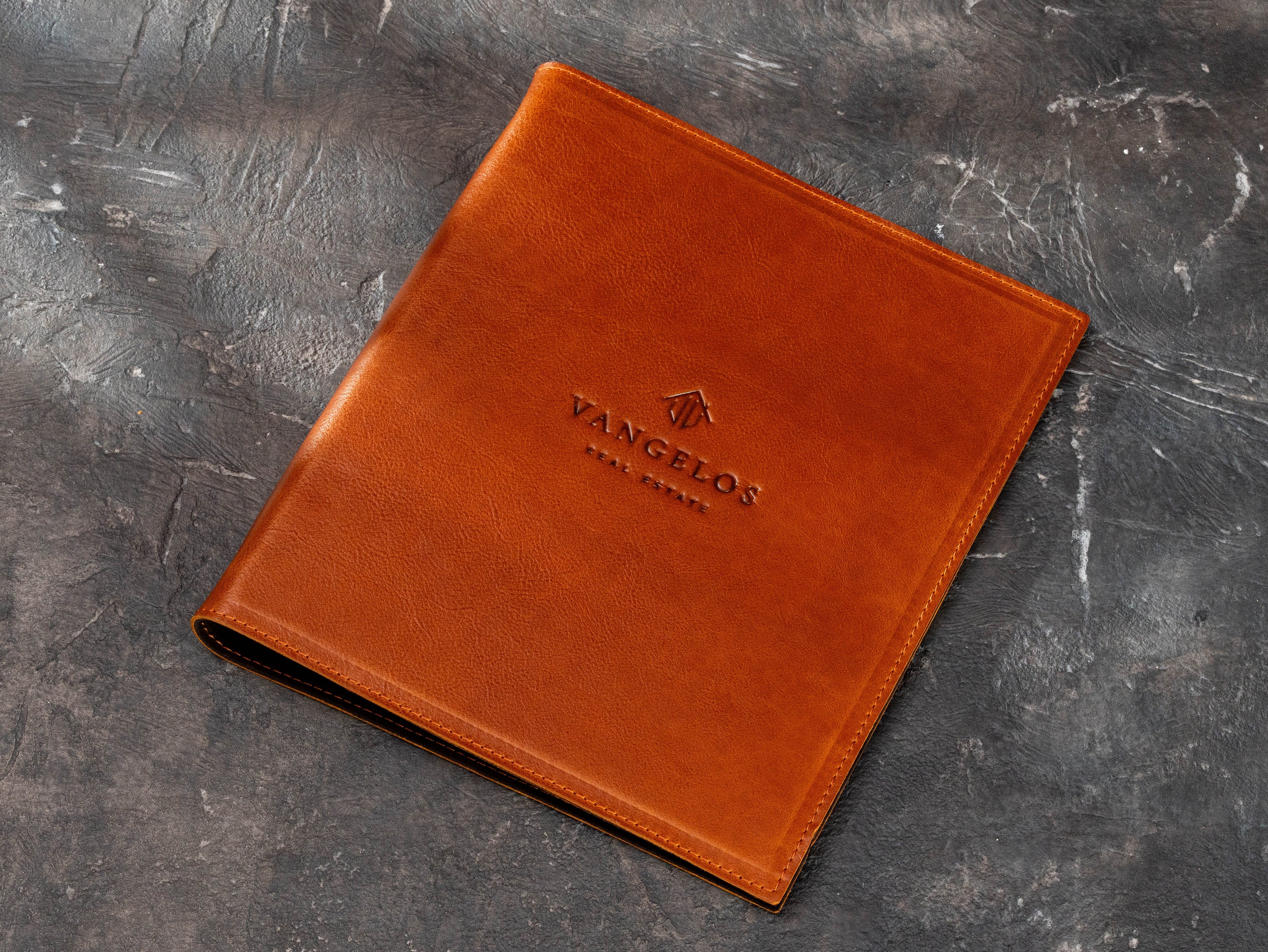 Warm brown leather real estate binder with custom company logo and 3-ring document organizer design.