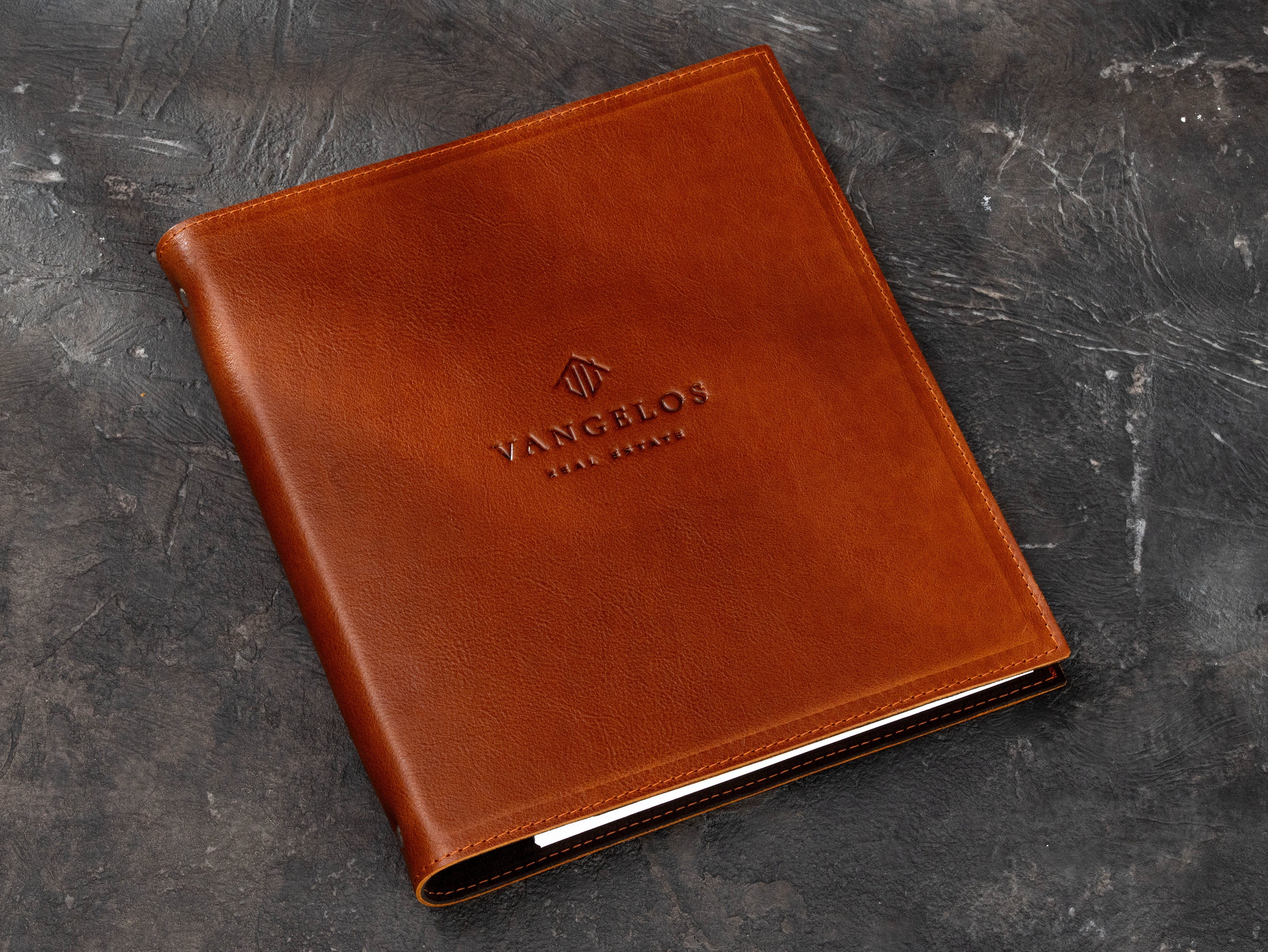 Premium brown leather 3-ring binder with custom real estate company logo and professional presentation design.