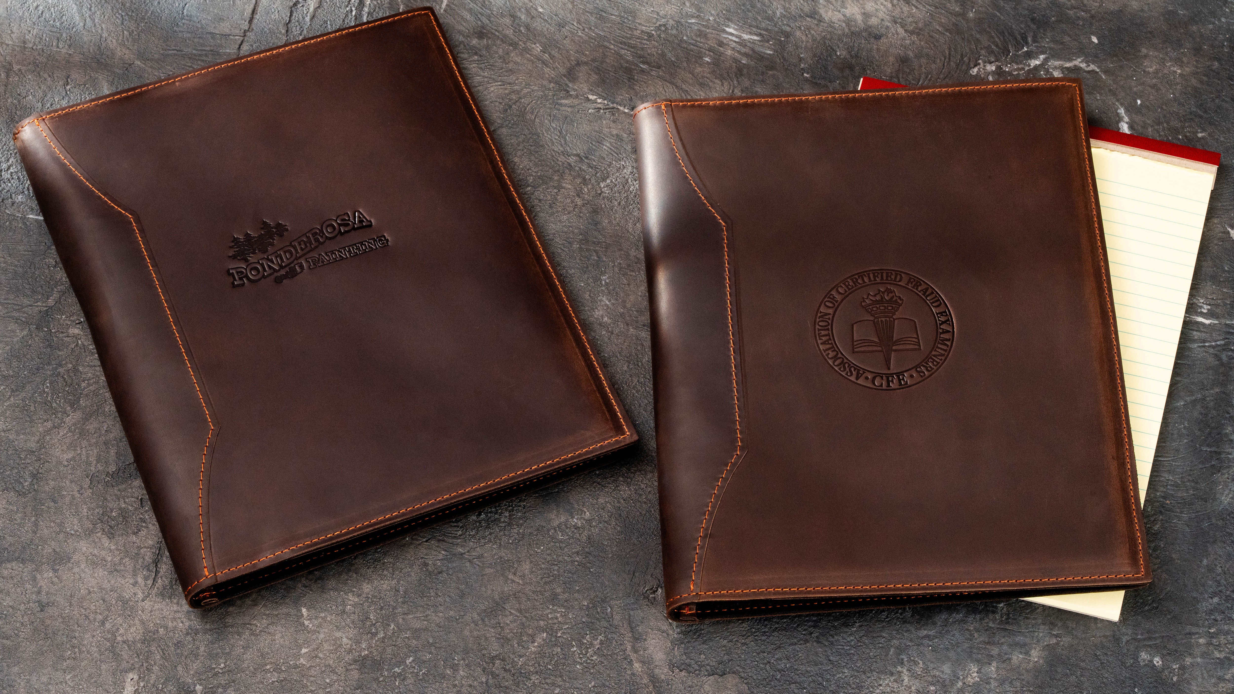 Two dark brown leather business padfolios with different custom company and professional association logos, designed for US Legal Pads and corporate use.