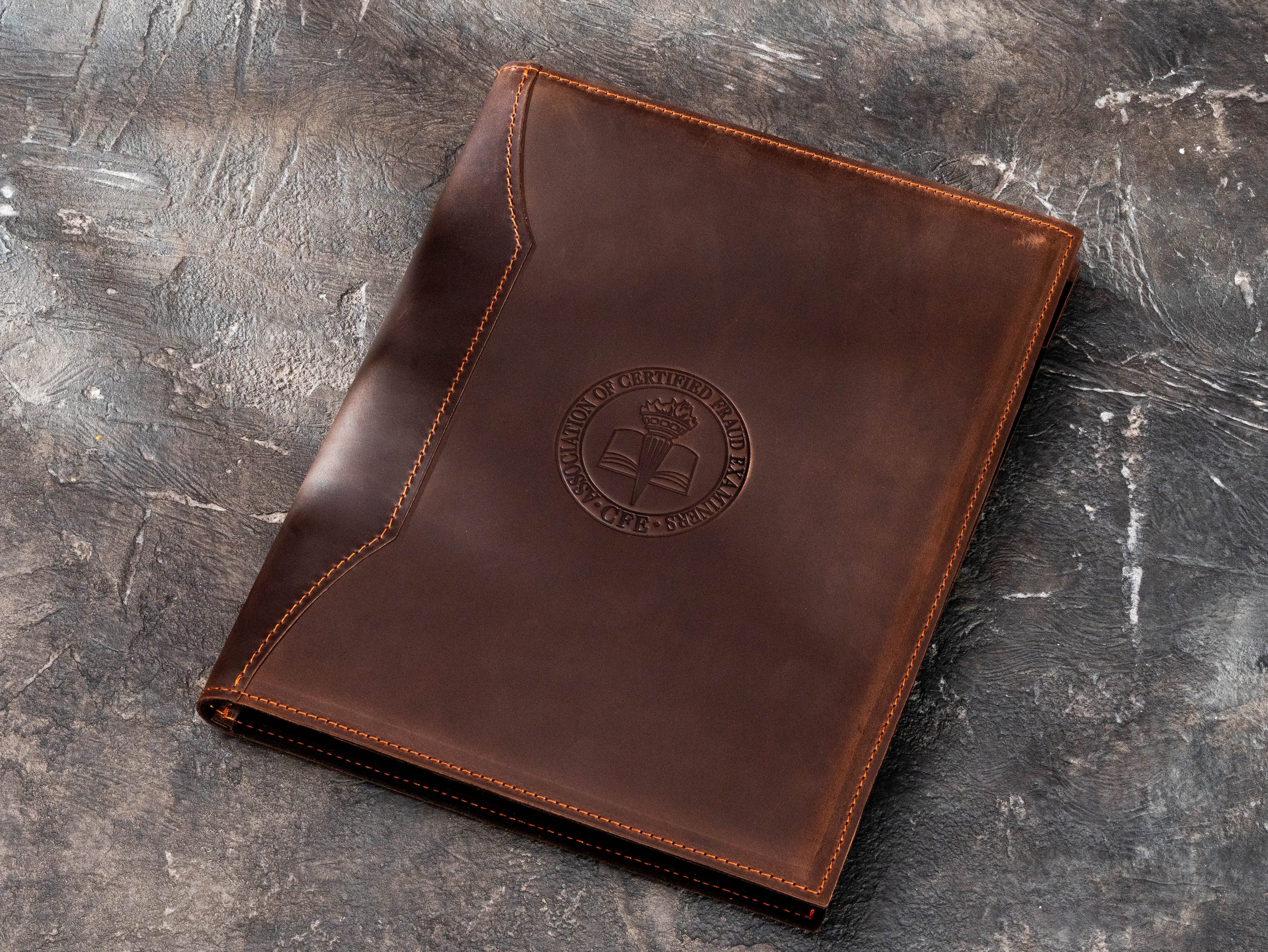 Angled view of personalized brown leather Legal Pad portfolio with professional association emblem and stitched business padfolio construction.