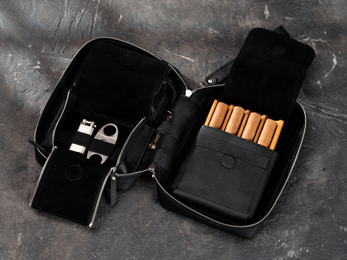 Black leather cigar event case with removable oak tray for cigars, organized accessory compartments, elastic holders and zipper access.