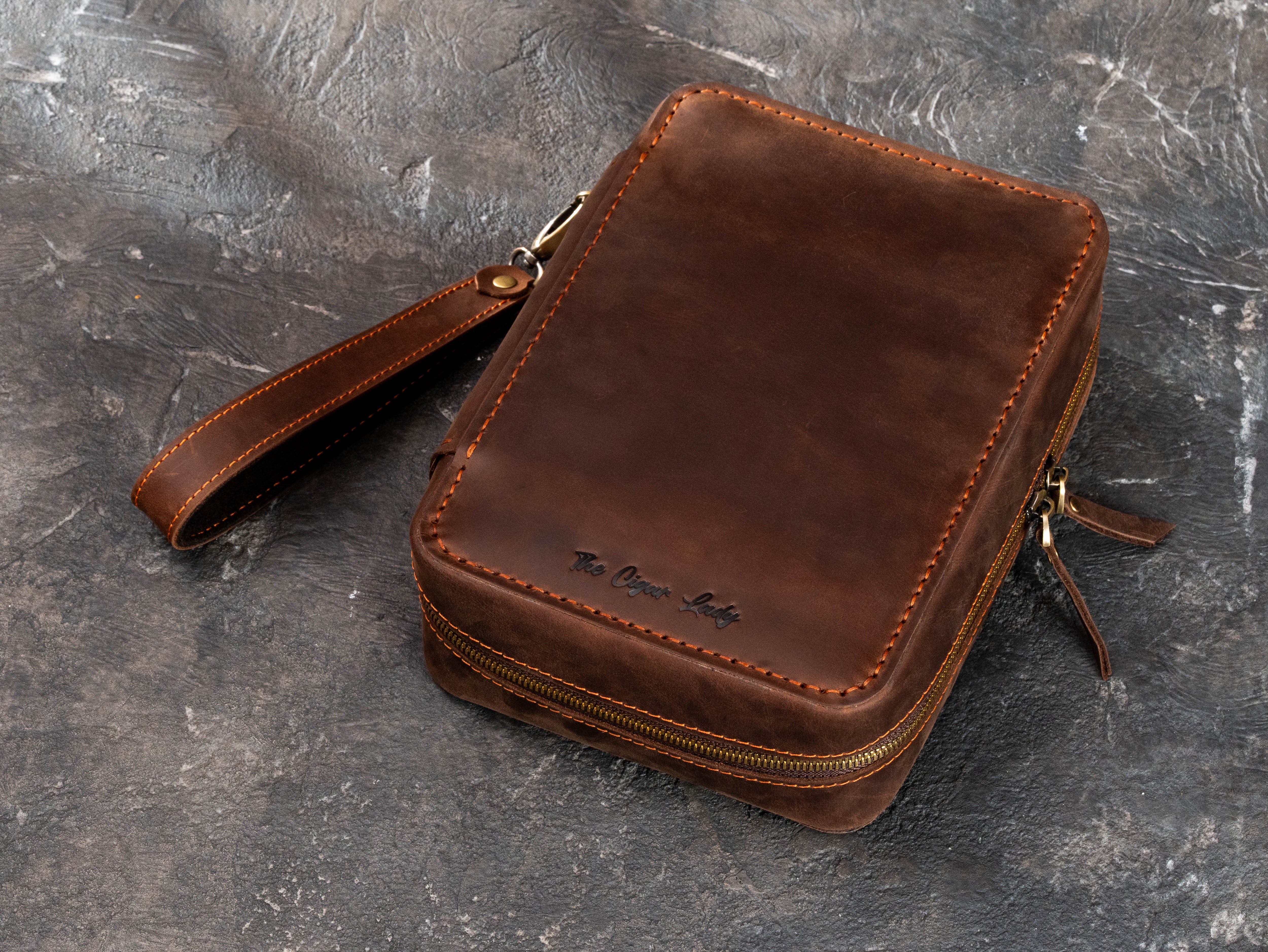 Personalized dark brown leather cigar organizer with dual zipper closure, removable wrist strap and custom embossed text.
