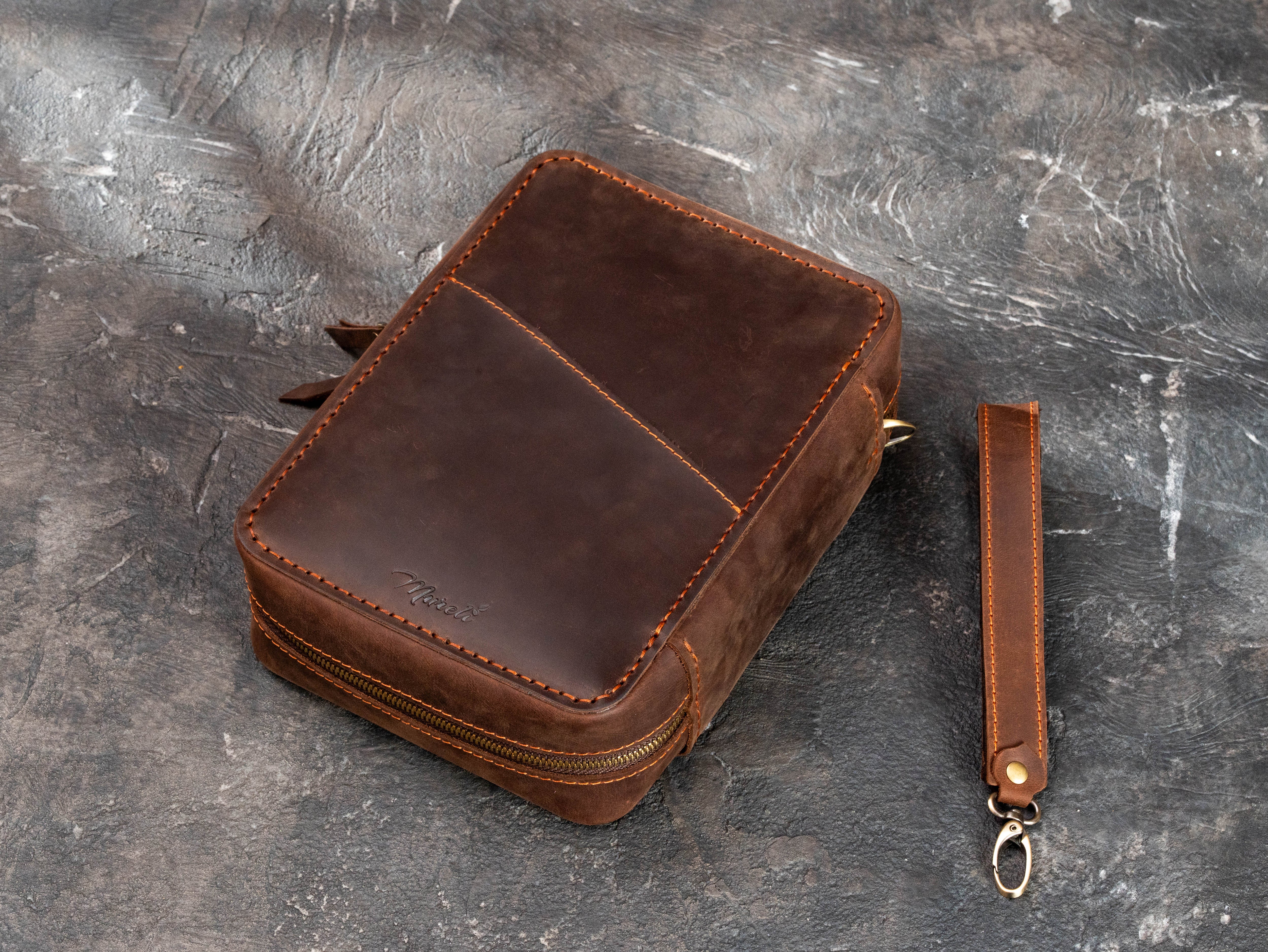 Back view of personalized brown leather cigar organizer showing large exterior phone pocket and removable wrist strap.