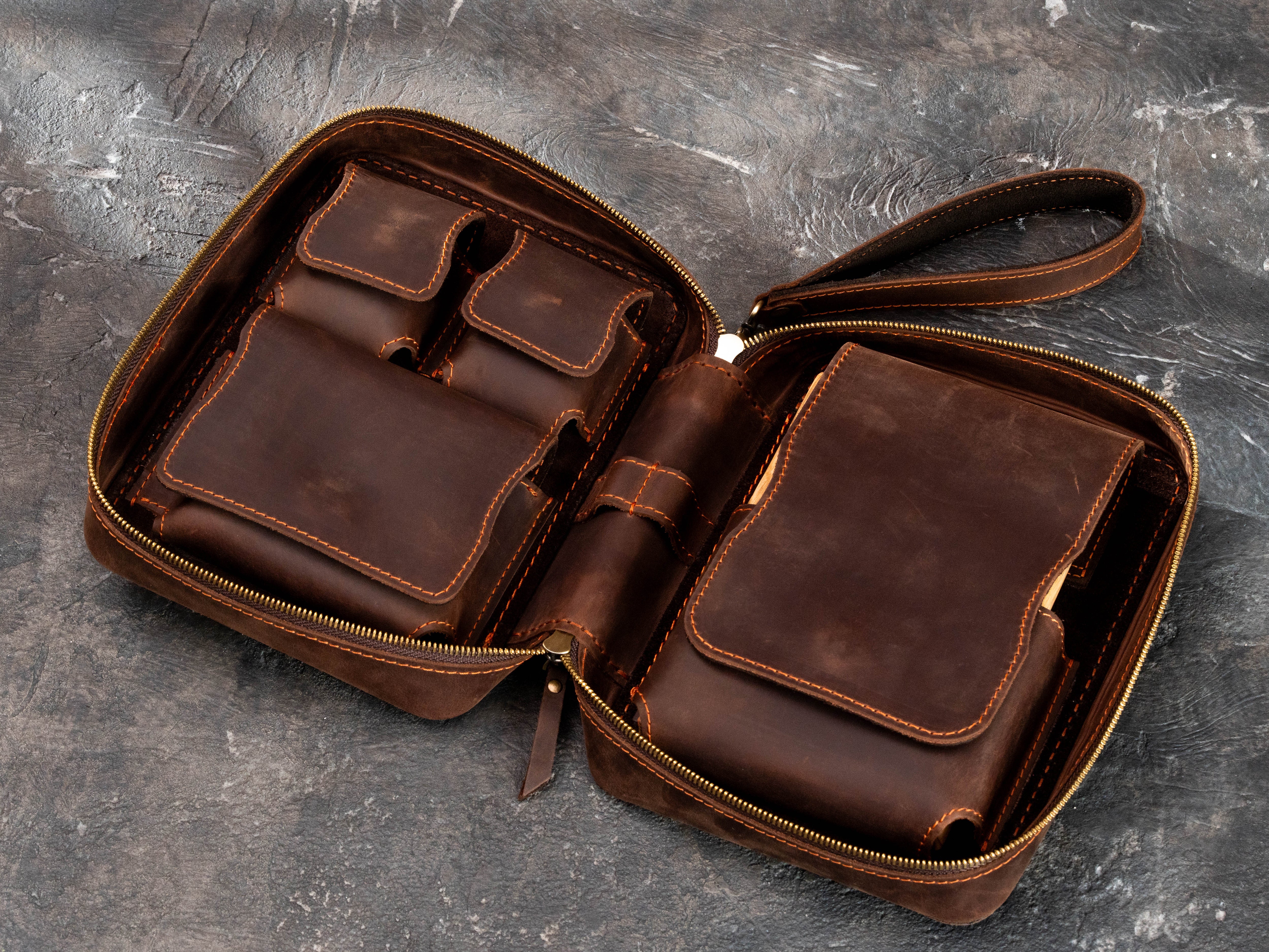 Open brown leather cigar organizer with sculpted accessory pockets, magnetic flaps, removable oak cigar tray section and wrist strap.