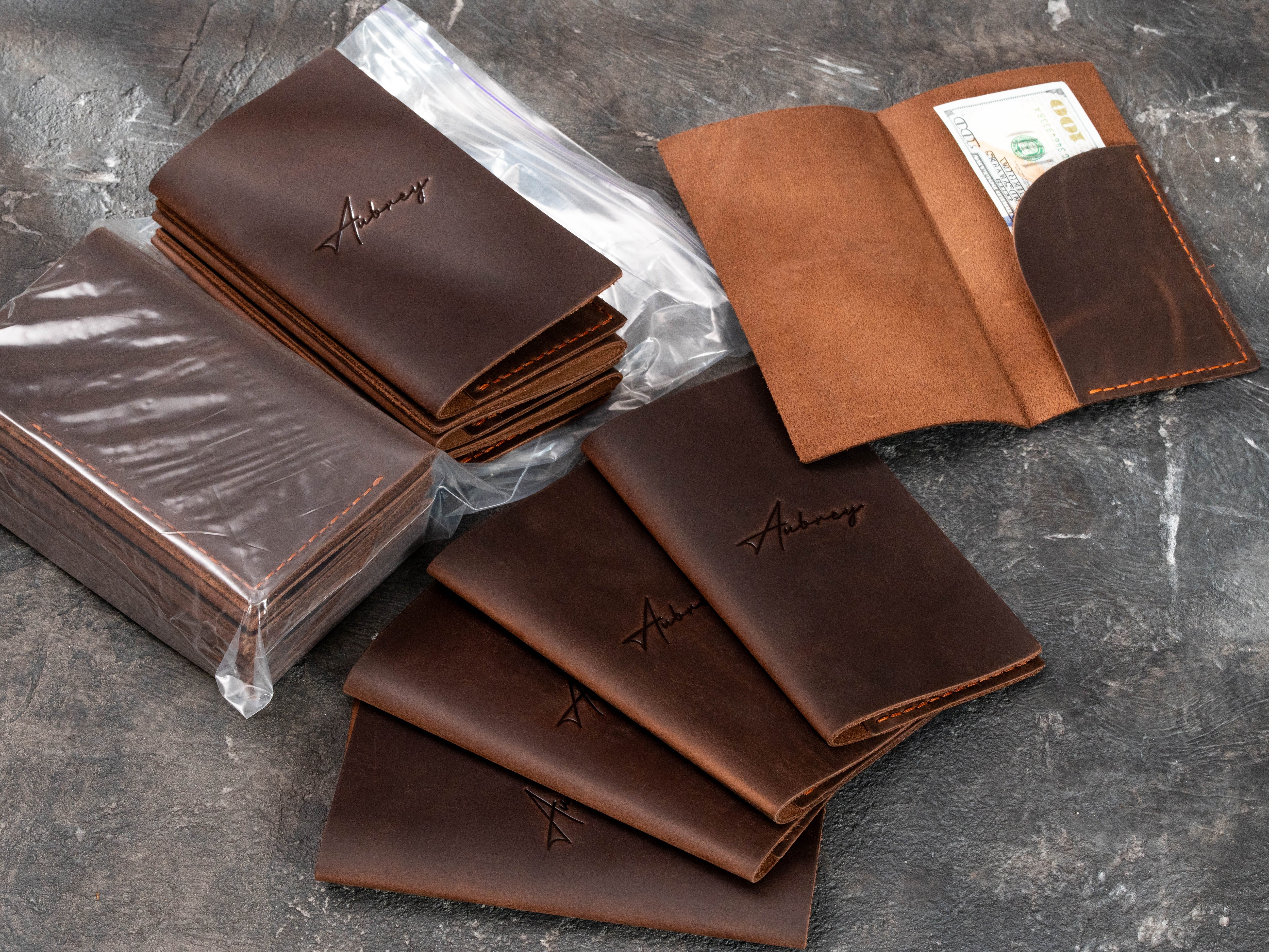 Bulk order of brown leather restaurant guest check holders with Aubrey logo, including open Design No. 1 bill holder with cash pocket.