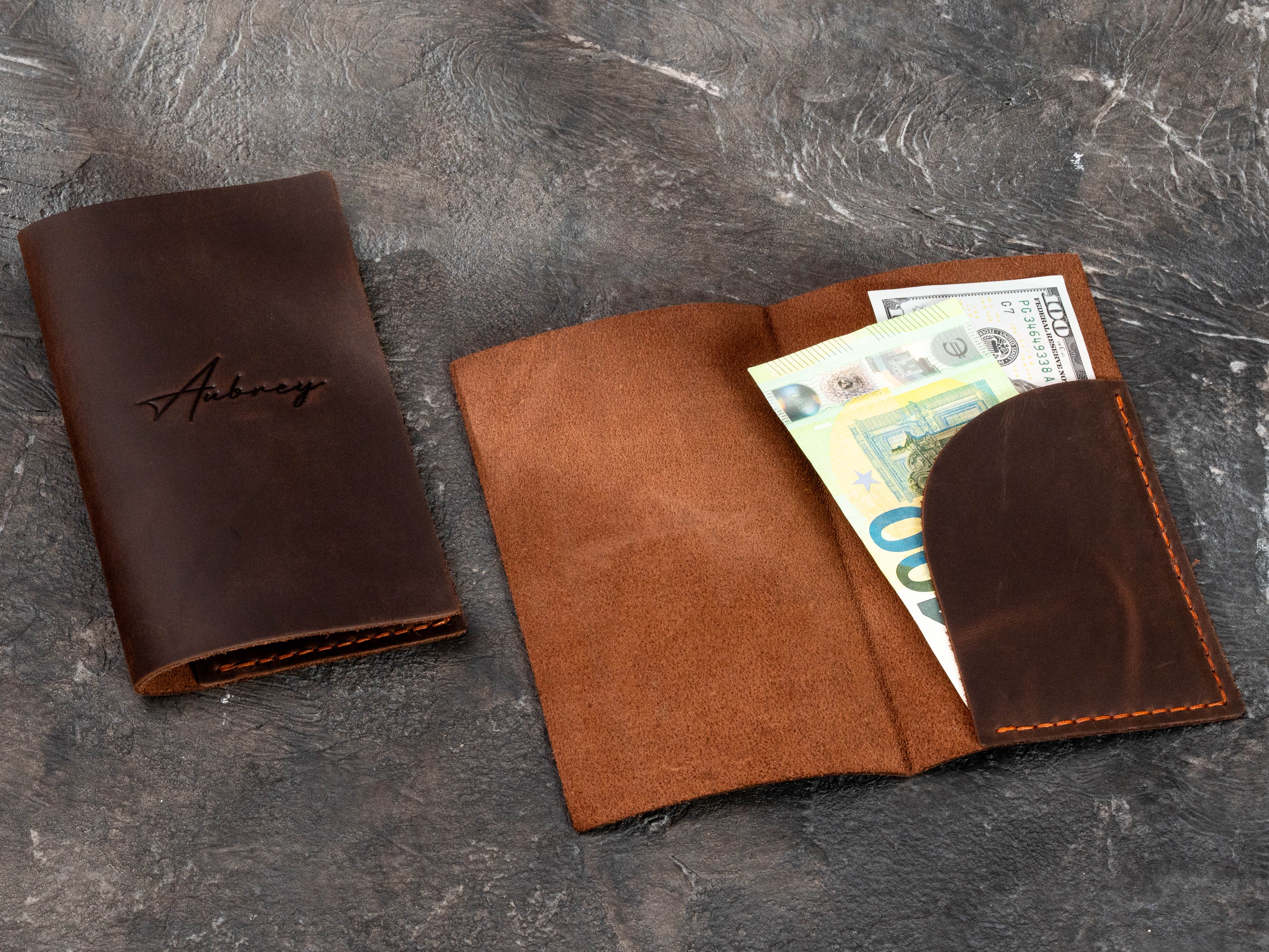 Brown leather restaurant bill holder shown open with curved cash pocket holding US dollars and euro banknotes.