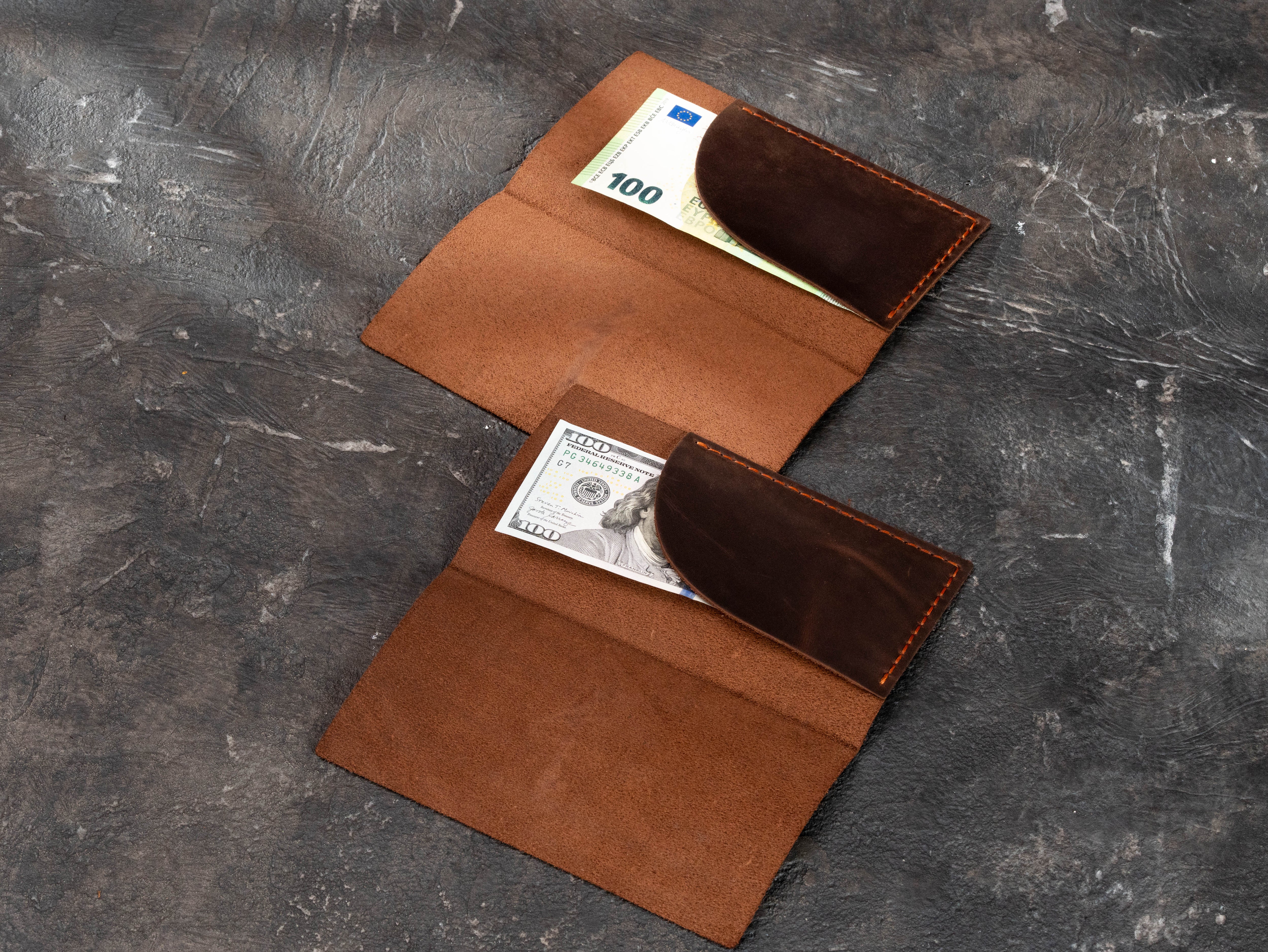 Two open brown leather Design No. 1 check presenters showing curved receipt and cash pockets for different currencies.