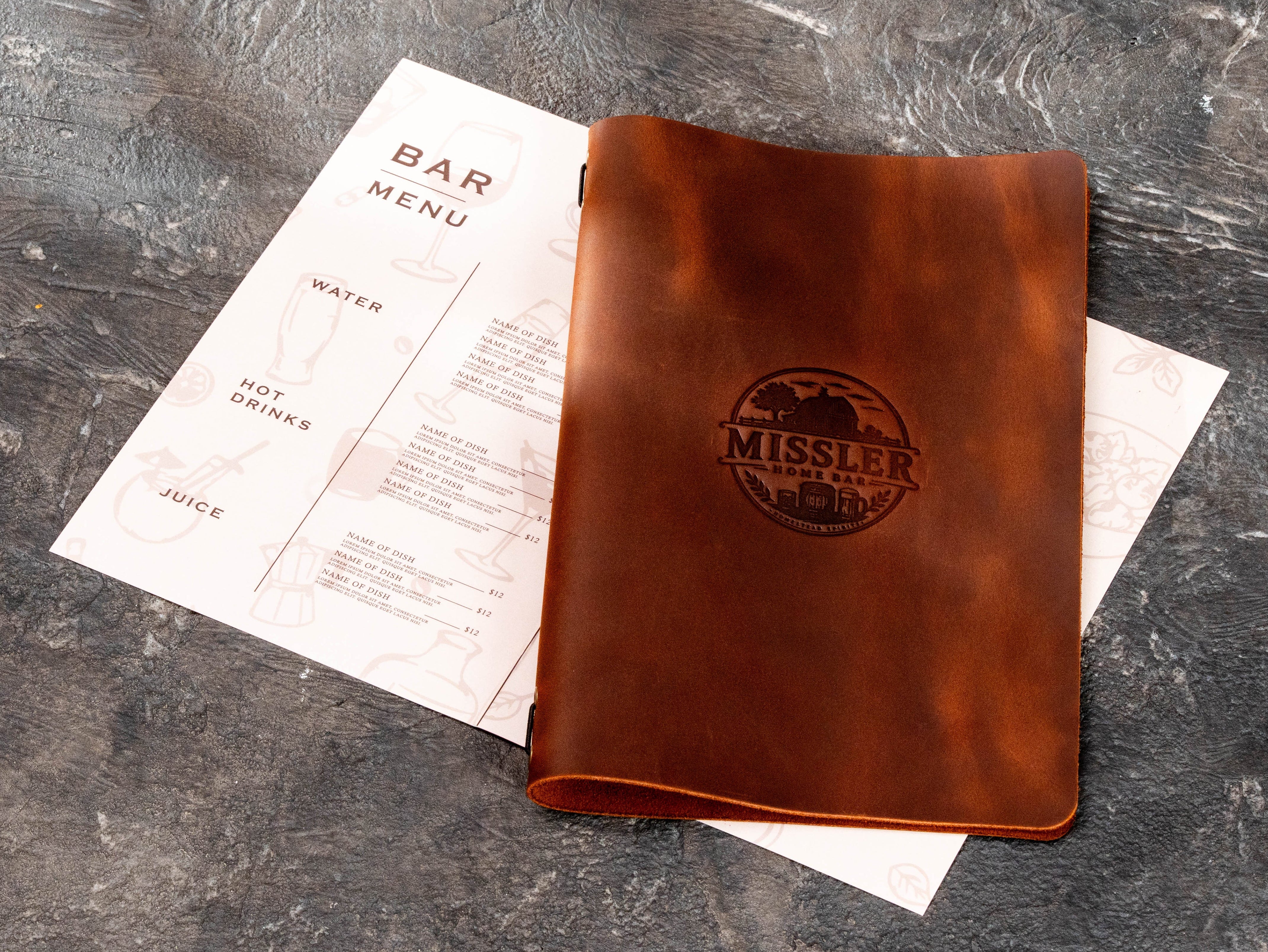 Personalized brown leather home bar menu cover with custom embossed logo displayed beside a printed bar menu.