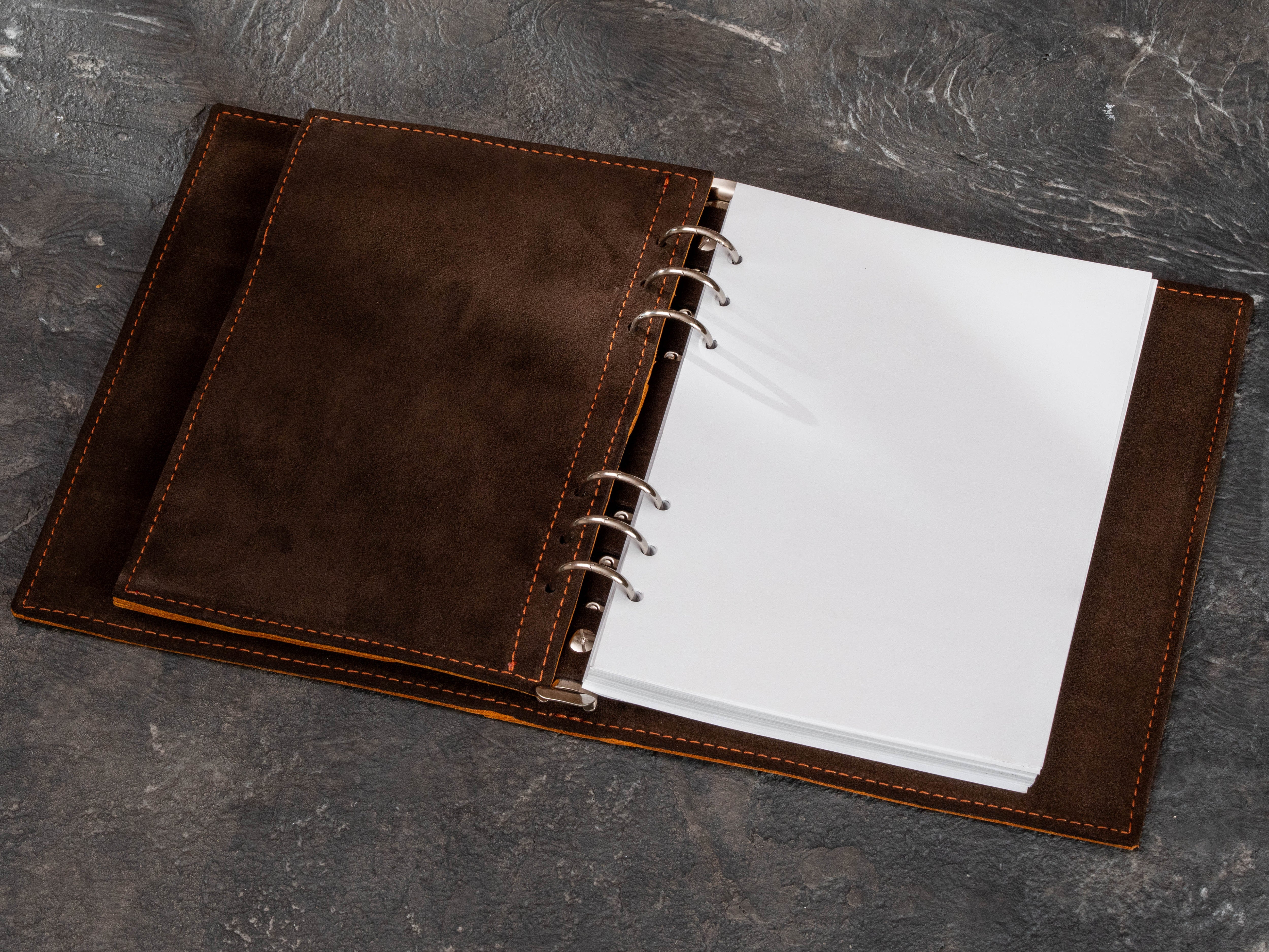 Open Camel leather refillable binder with dark suede divider, six-ring mechanism and replaceable blank A5 paper pages.