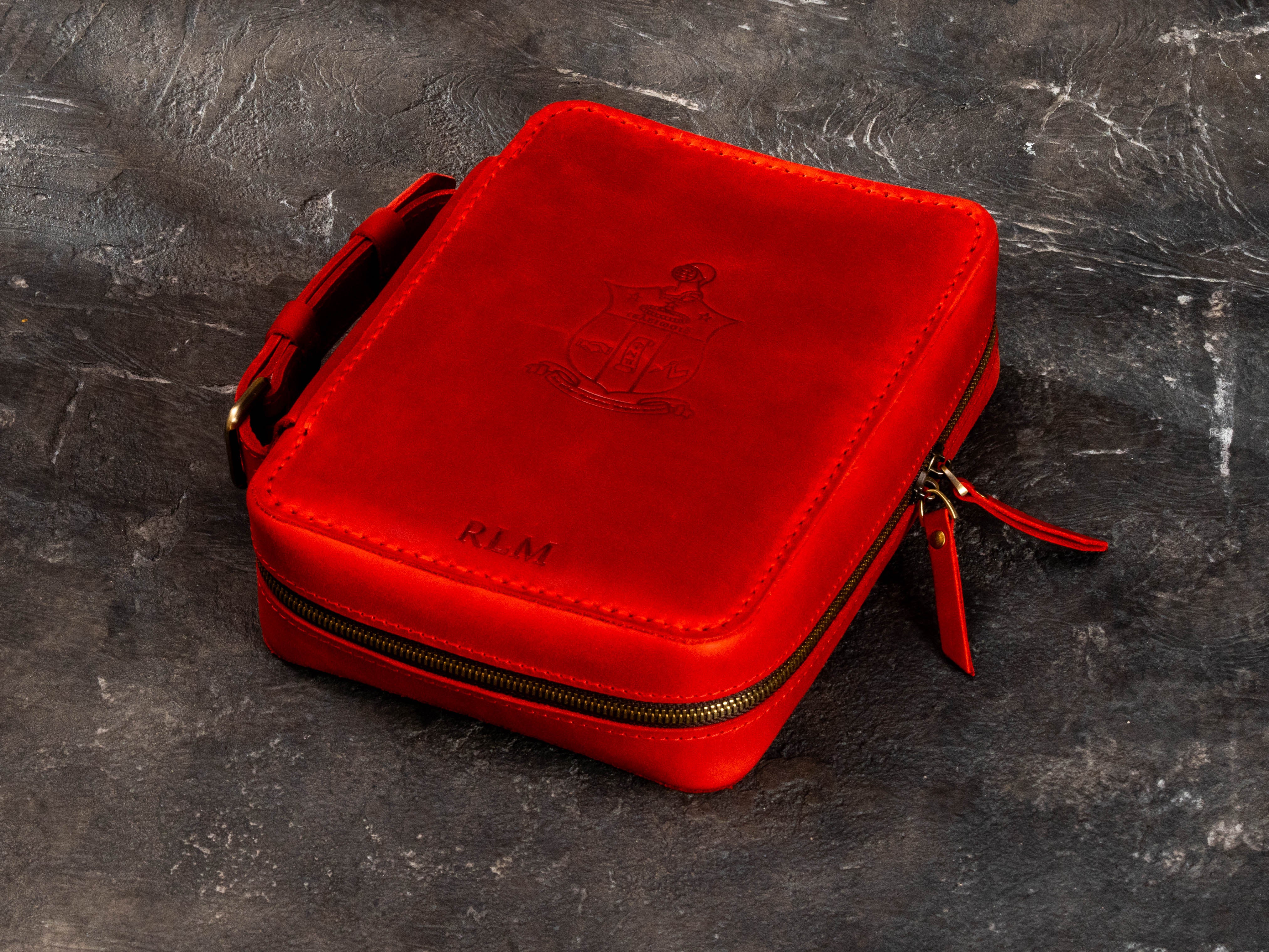 Custom red leather cigar organizer with embossed crest and individual initials on the front cover.