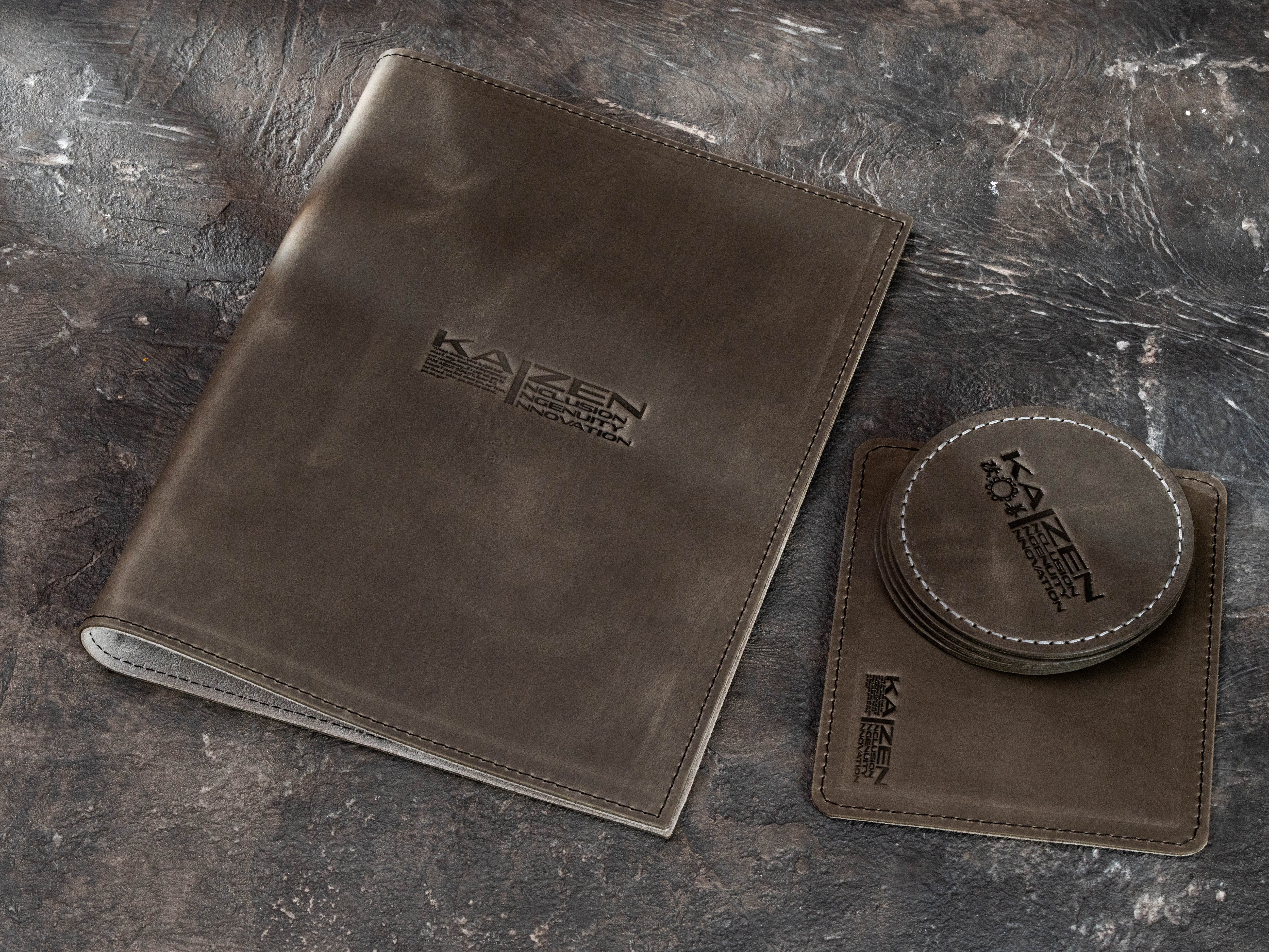 Gray Crazy Horse leather corporate binder displayed with matching branded leather coasters and equipment mat.