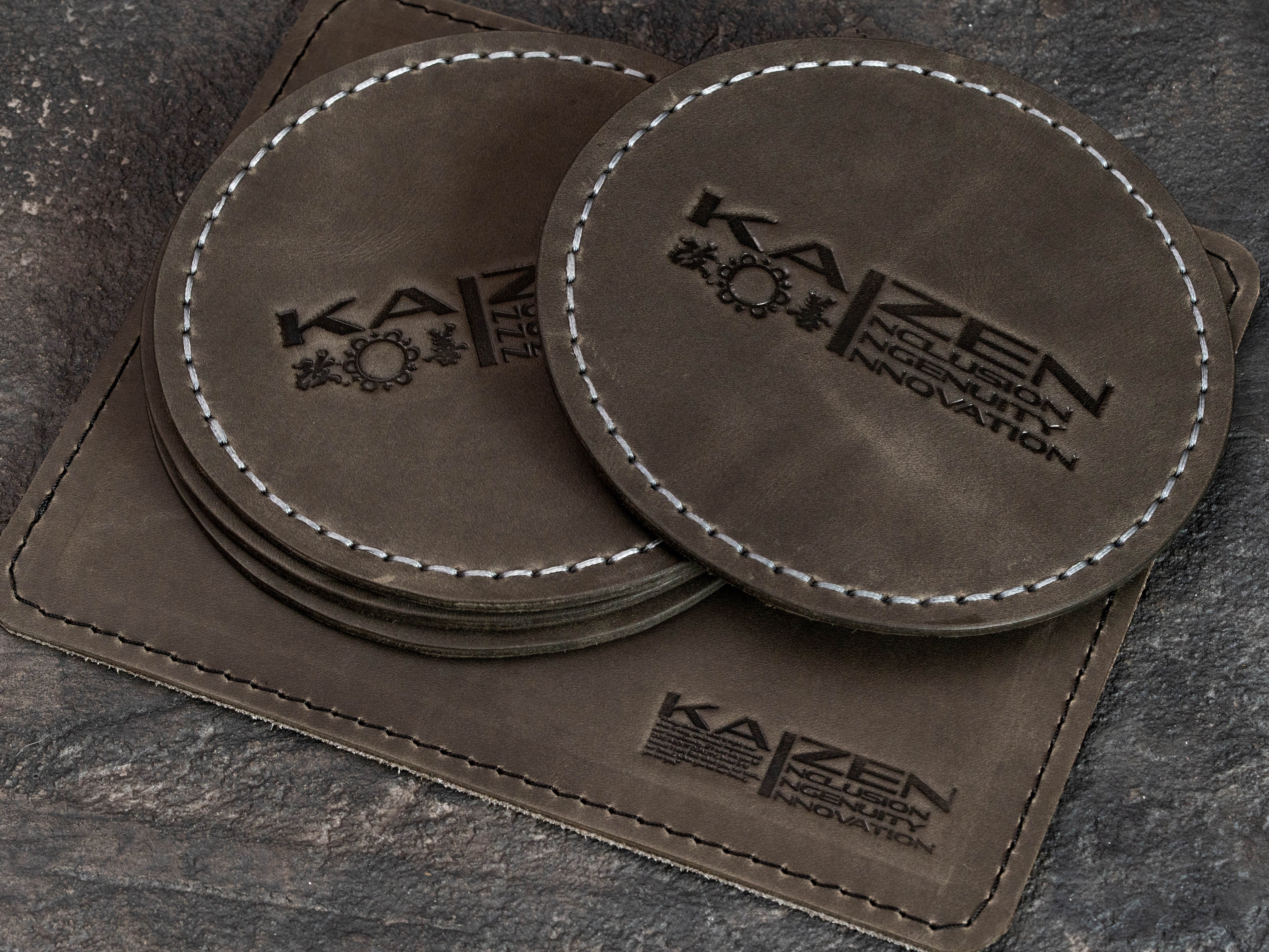 Custom Gray Crazy Horse leather coaster set and rectangular equipment mat with matching corporate KAIZEN branding.