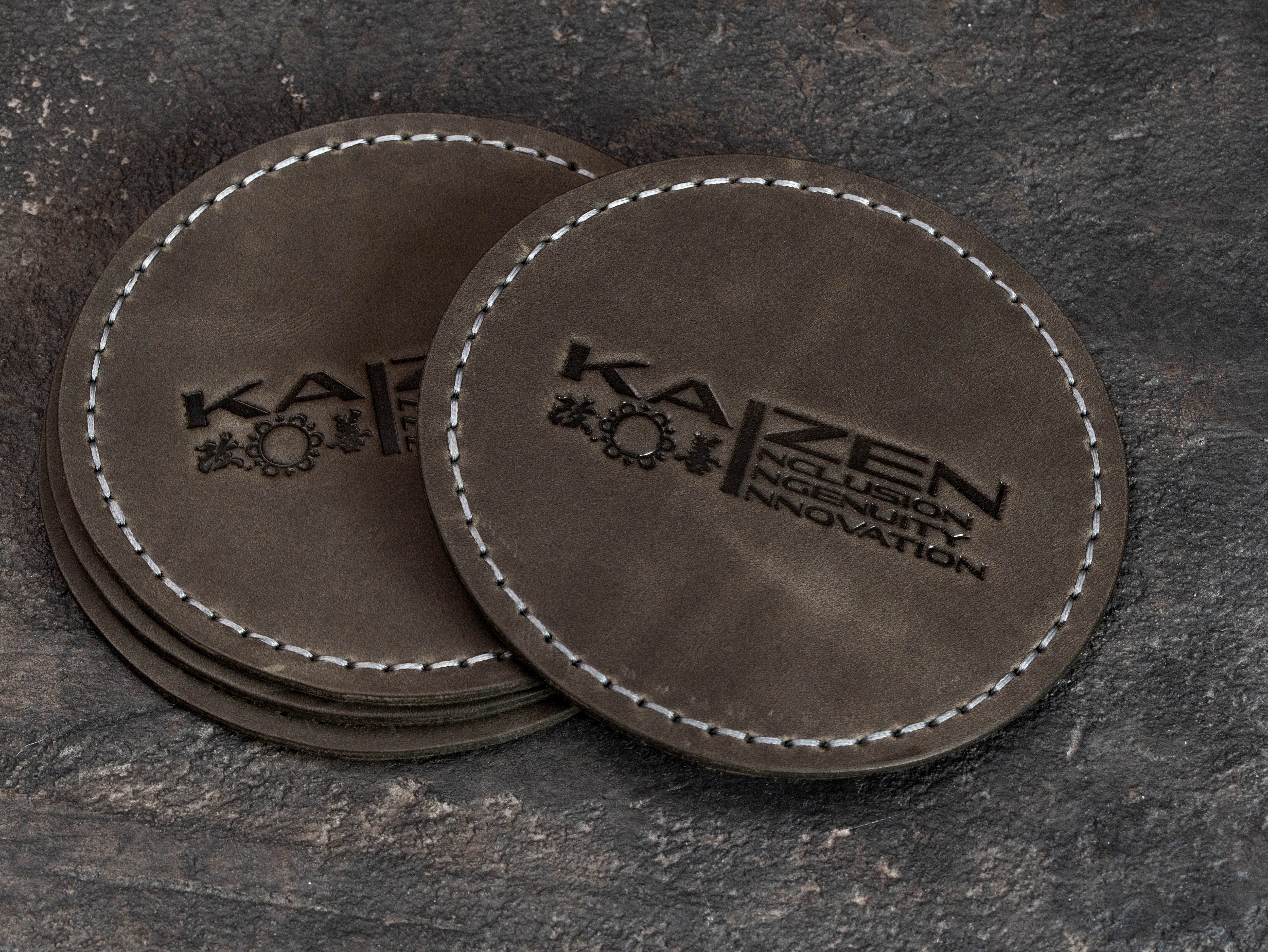 Stack of personalized Gray Crazy Horse leather coasters with hand stitching and custom corporate logo.