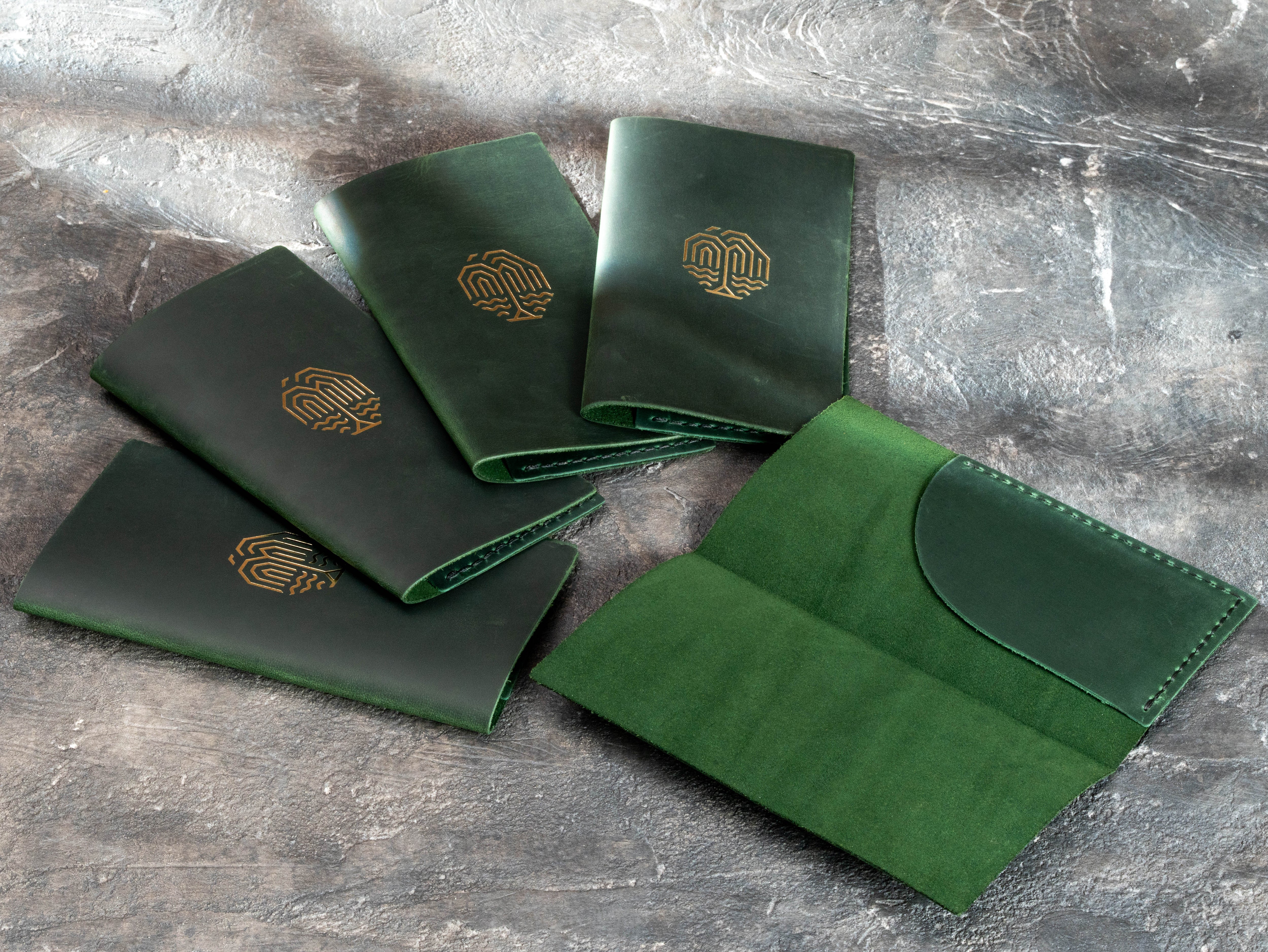 Custom green leather guest check folders with gold branding and a denser leather construction requested by the client.