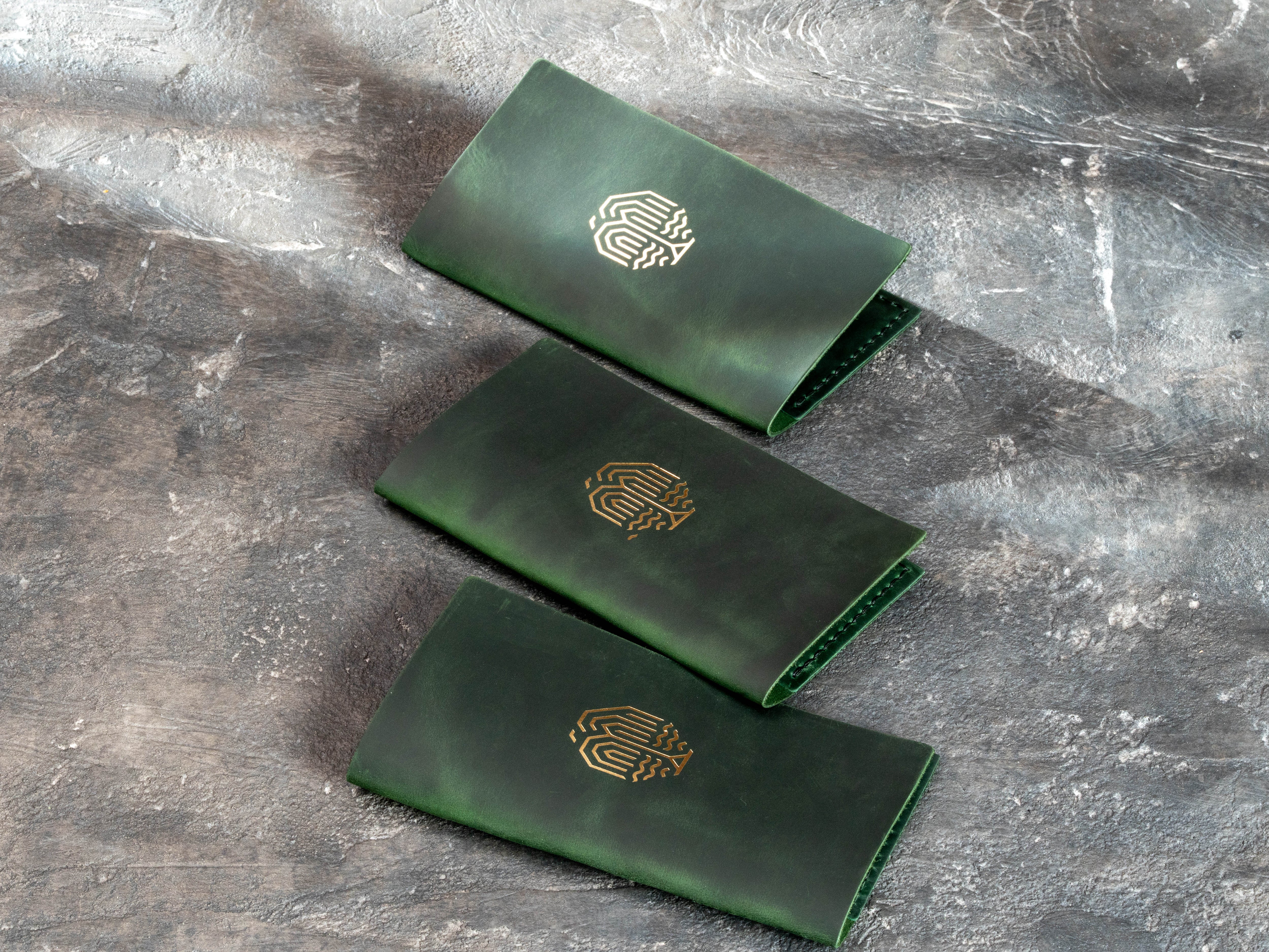 Green leather bill holders with custom logo personalization, designed for restaurant and hospitality use.