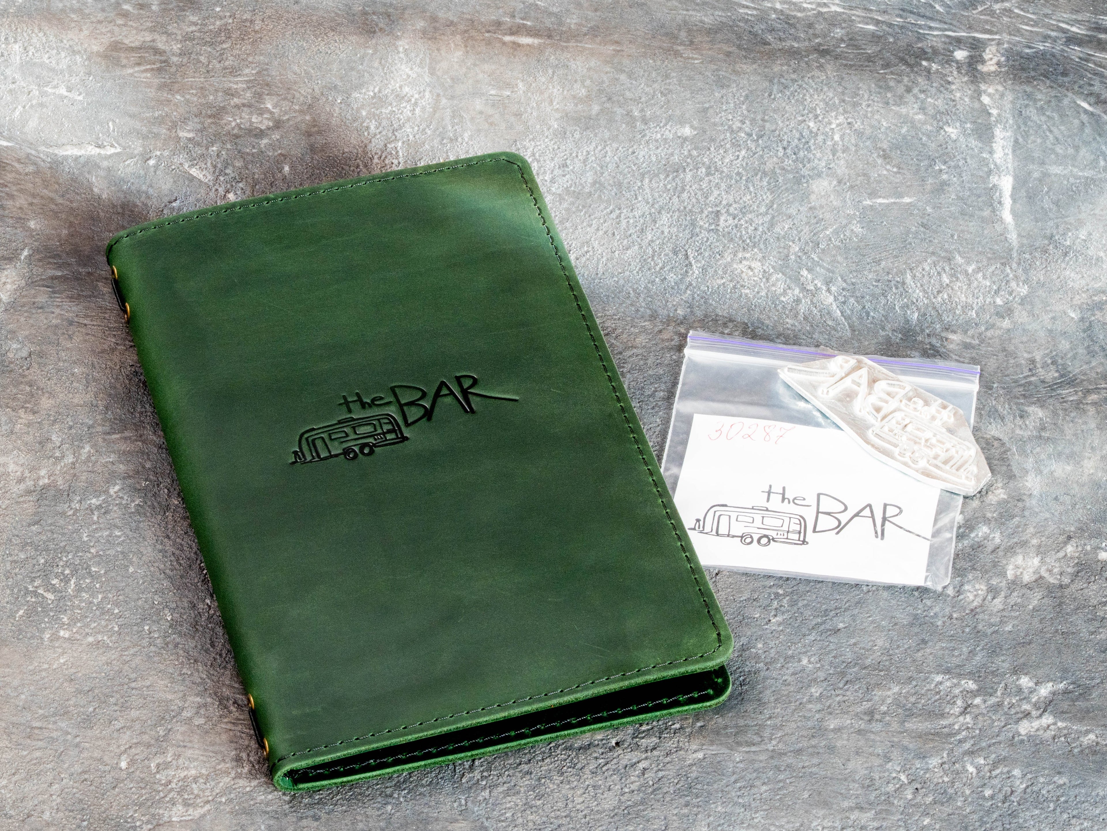 Custom leather bar menu cover shown with logo embossing and matching embossing die.
