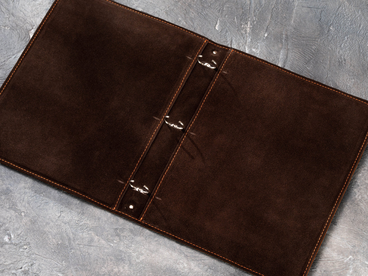 Three-ring leather presentation binder open to show suede-lined interior and ring mechanism