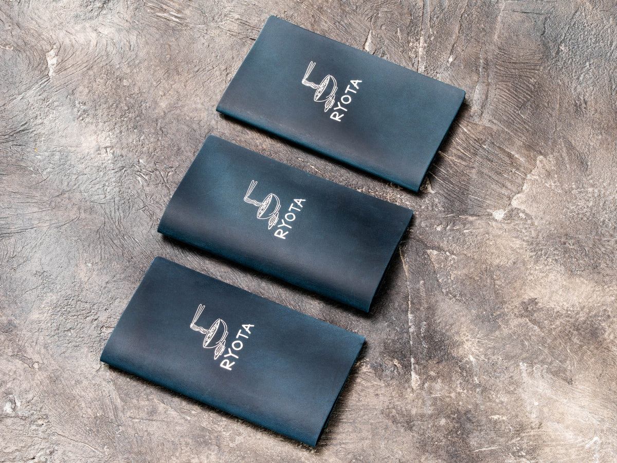 Set of custom dark blue leather restaurant check presenters with silver foil branding
