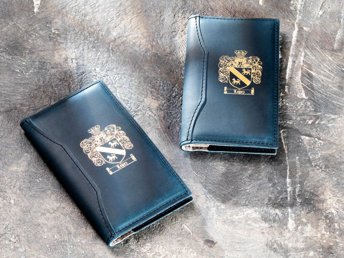 Custom navy blue leather guest check presenters with gold crest logo for fine dining and hospitality