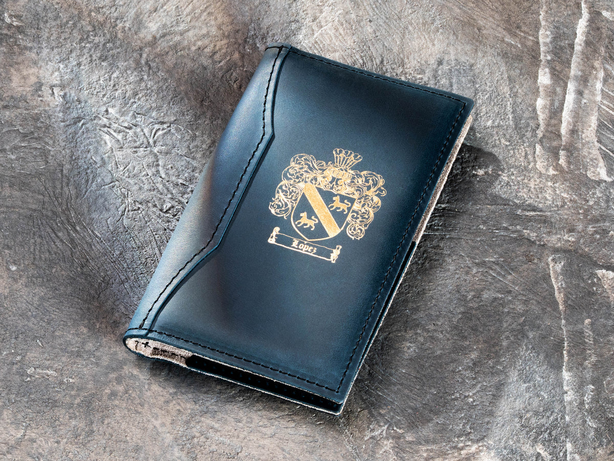 Navy leather restaurant bill presenter with gold foil family crest and stitched edges