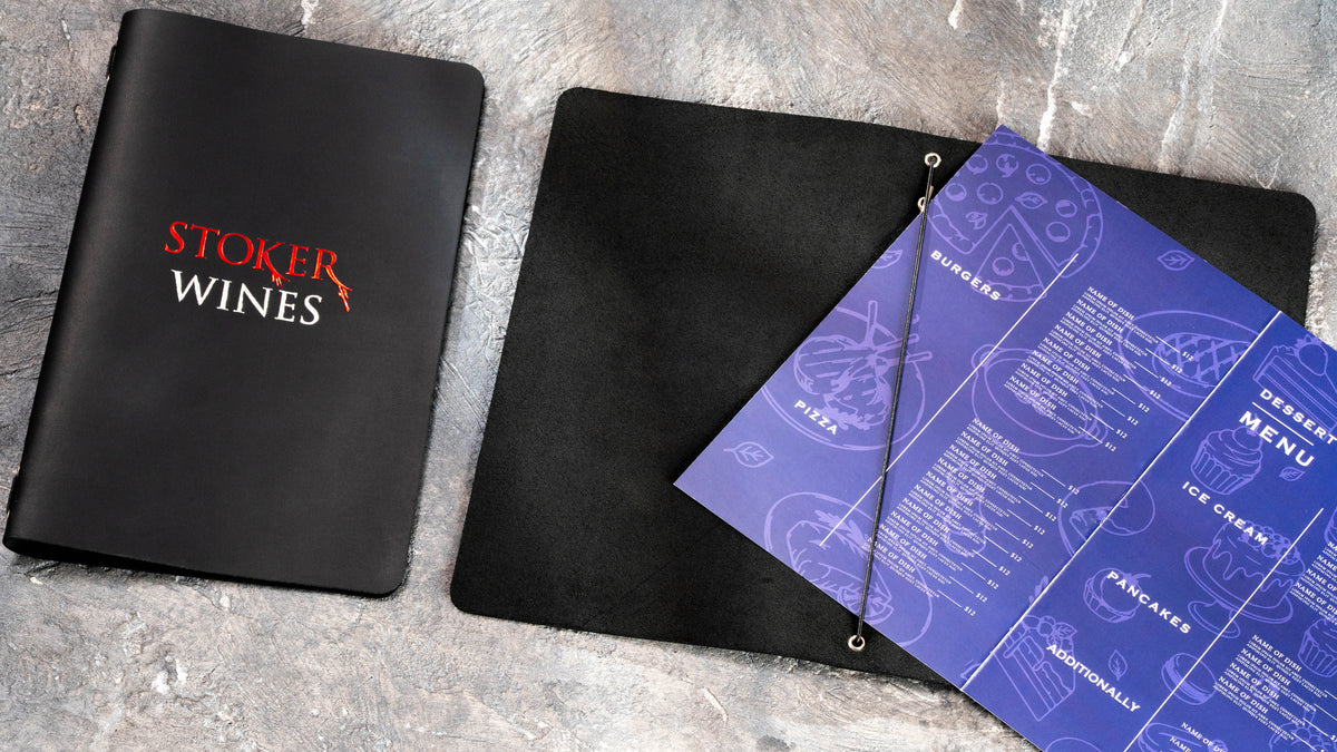 Folded menu insert being placed beneath the elastic cord inside a black leather Stoker Wines cover