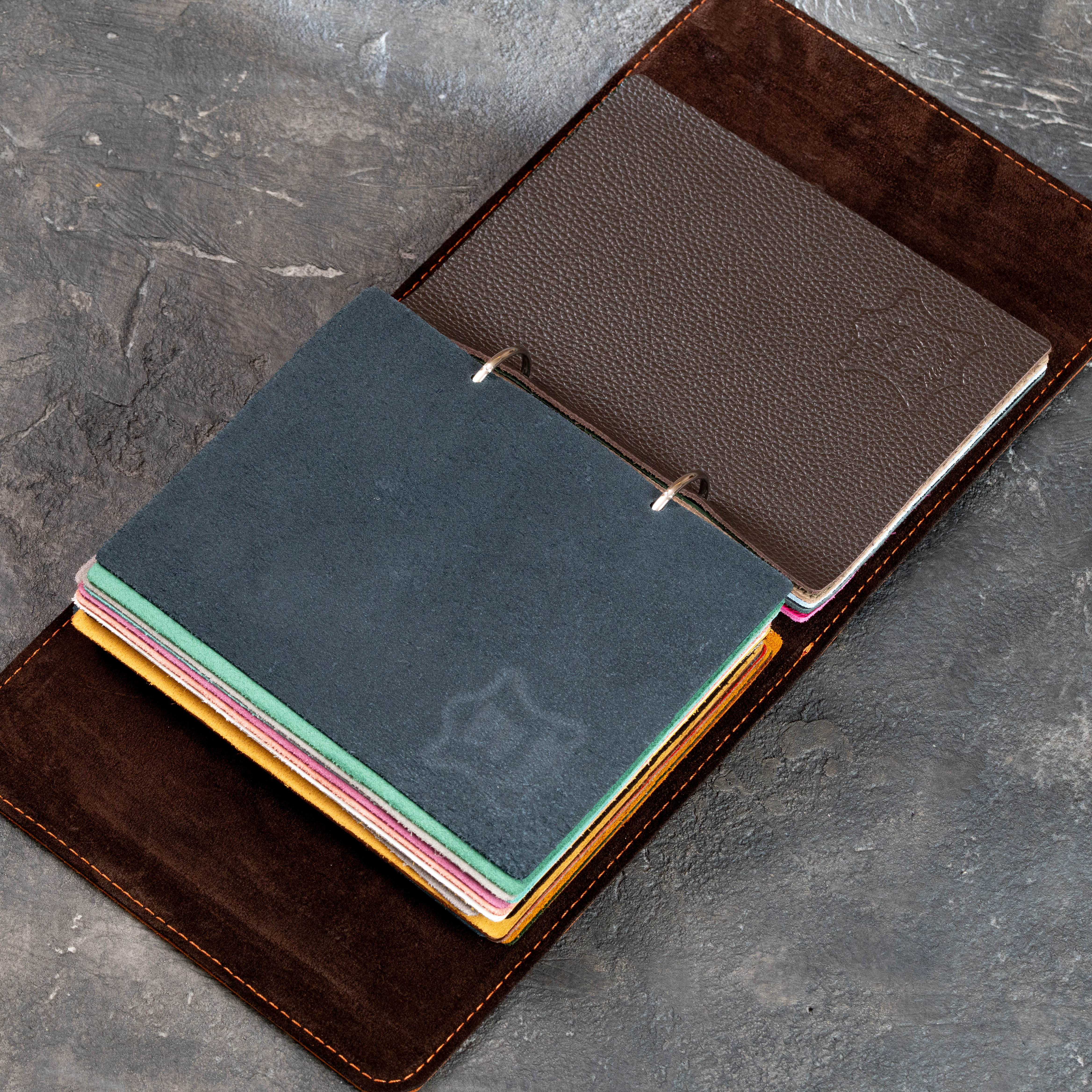 Open leather sample binder with metal rings and yellow, brown, and multicolor leather swatches