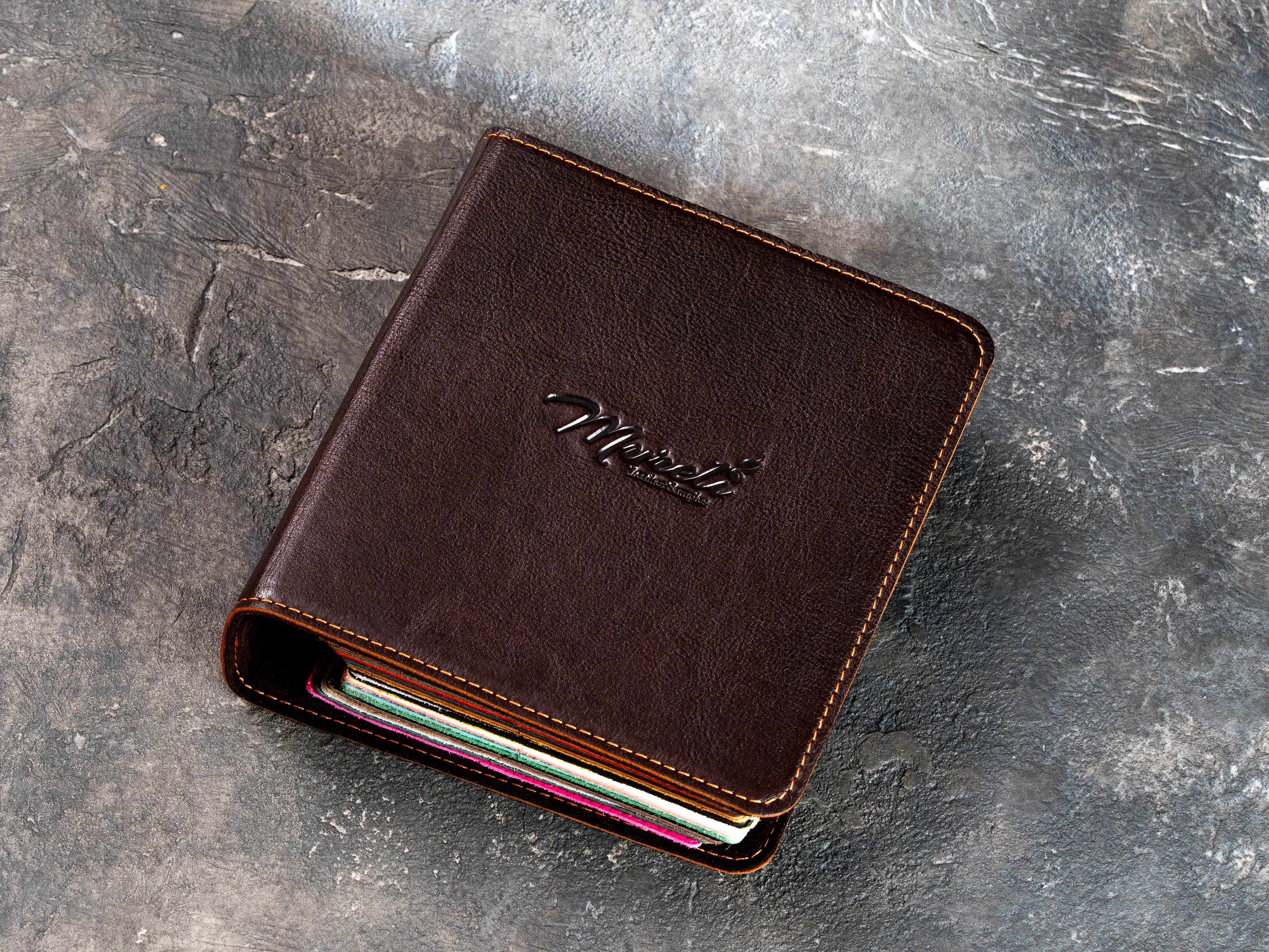 Closed dark brown leather sample binder with embossed Mureli logo and contrast stitching