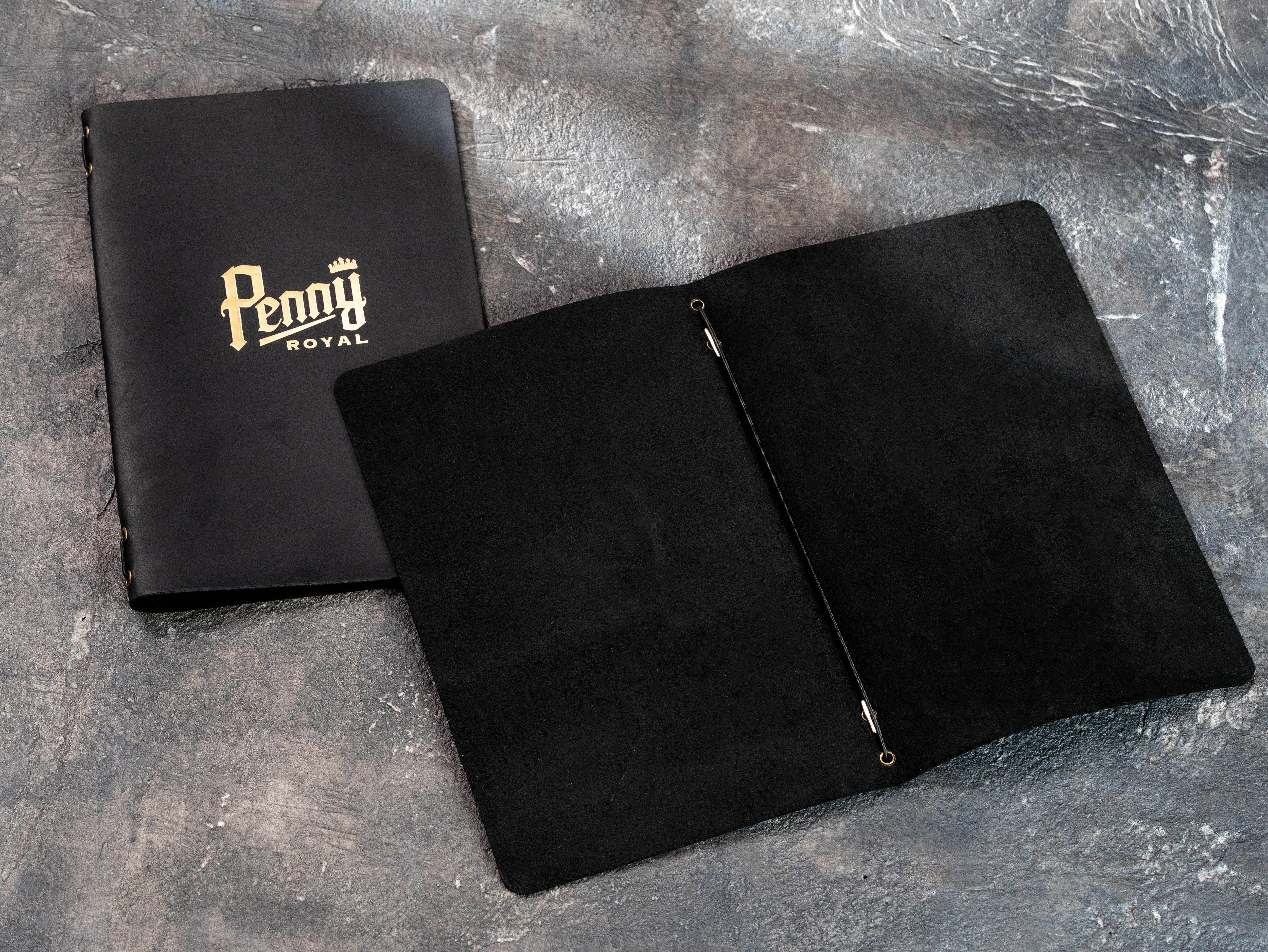 Open black leather menu cover with elastic cord holding folded printed restaurant menu pages