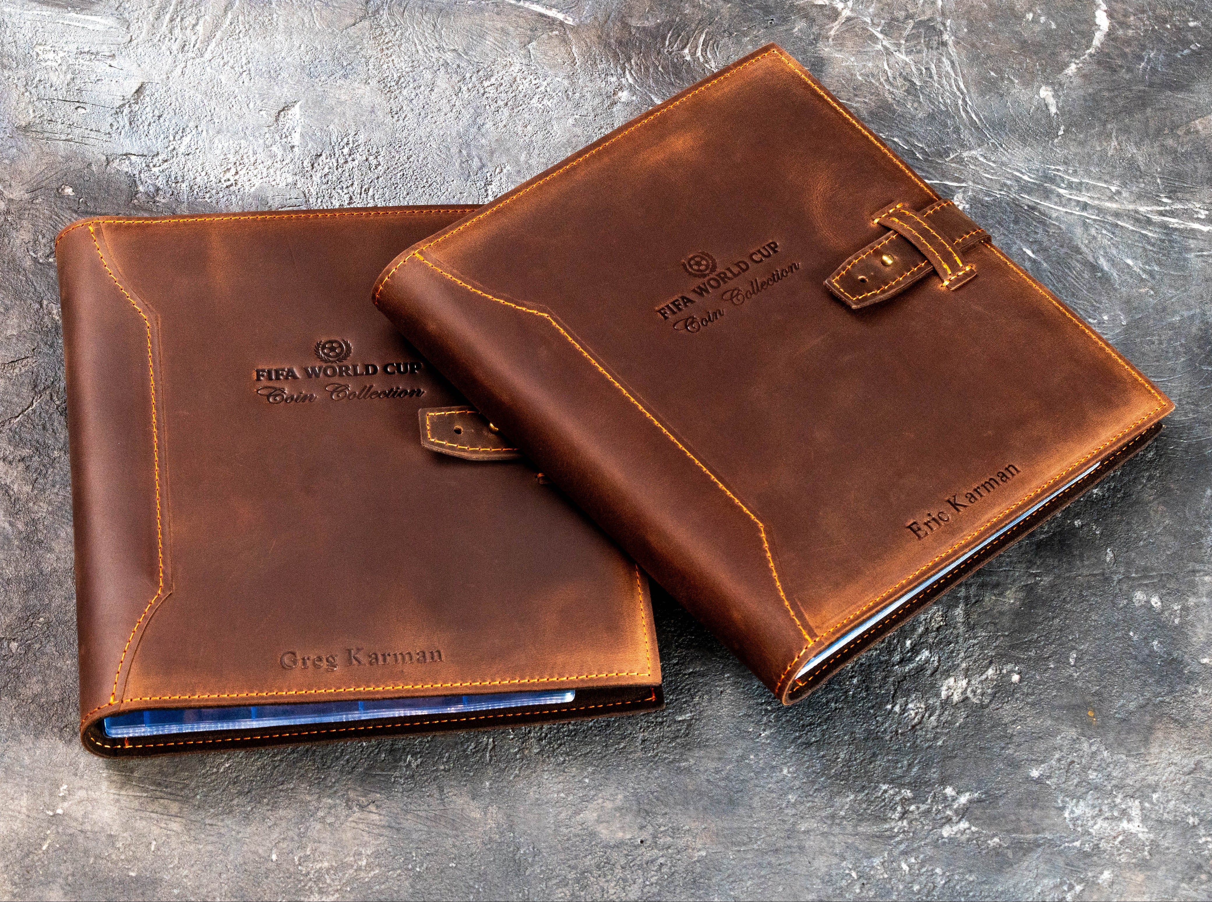 Pair of handcrafted brown leather coin albums with stitched covers, personalized designs, and brass stud closures