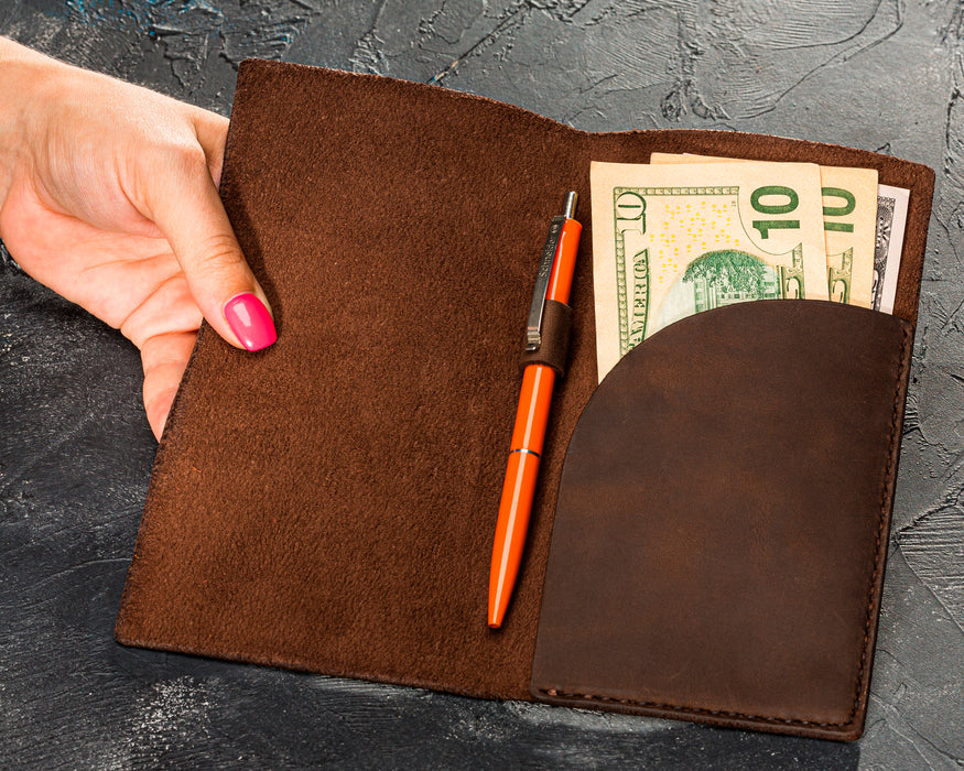 Brown leather guest check holder open with dollar bills inside