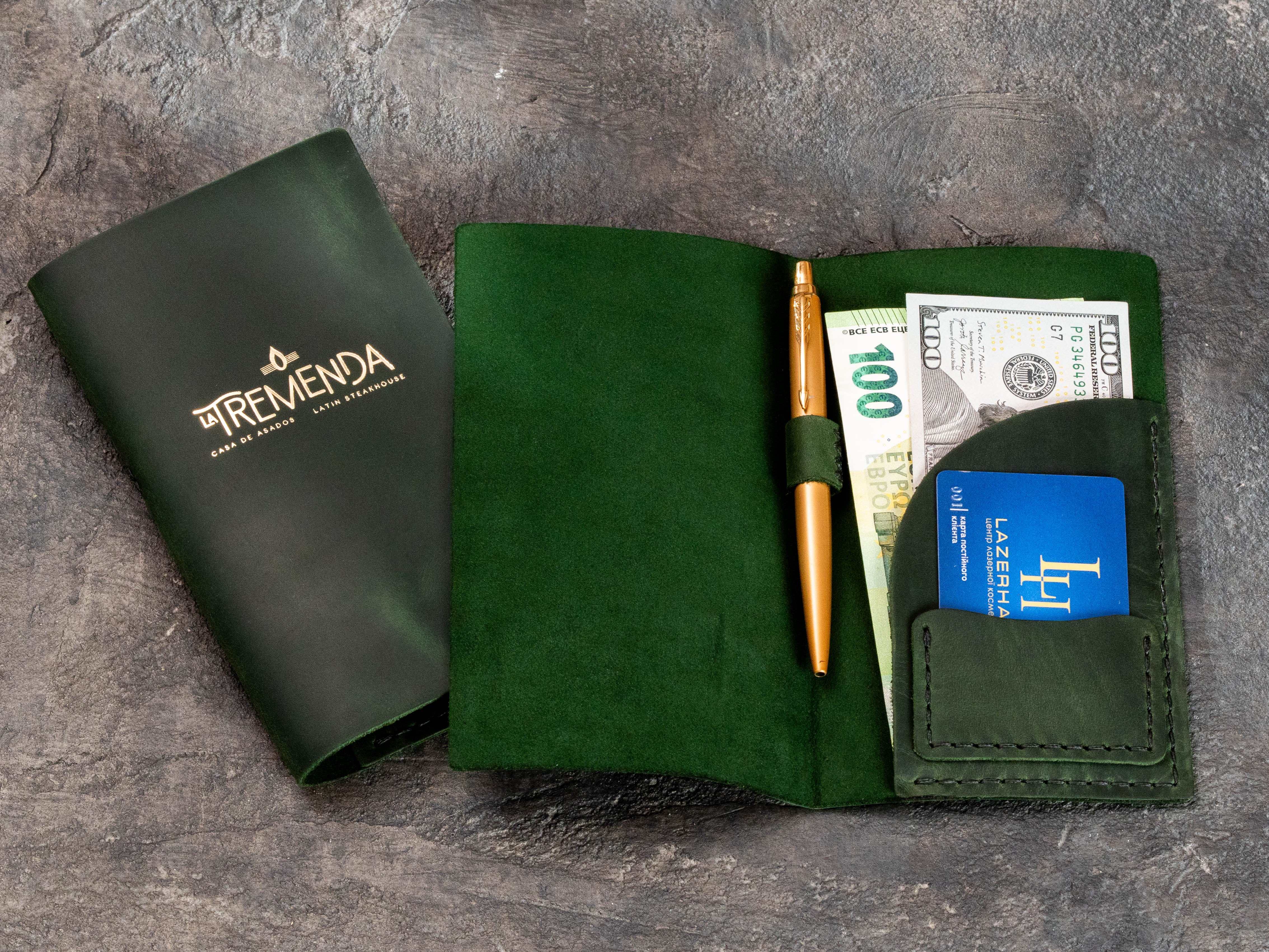 Open green leather check presenter with card pocket, bill pocket and pen loop for a Latin restaurant