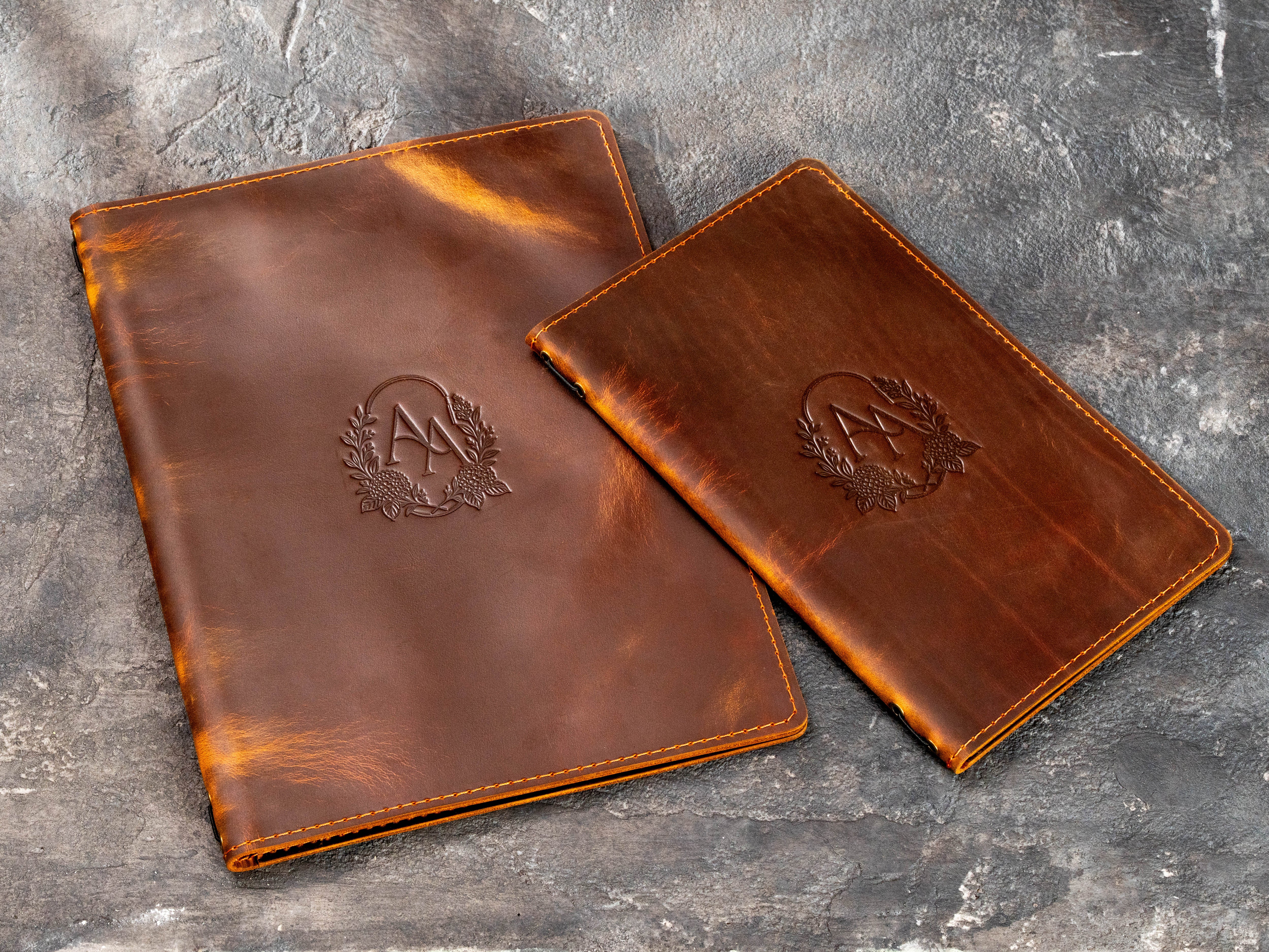 Custom brown leather menu covers with embossed floral monogram and stitched edges in two sizes