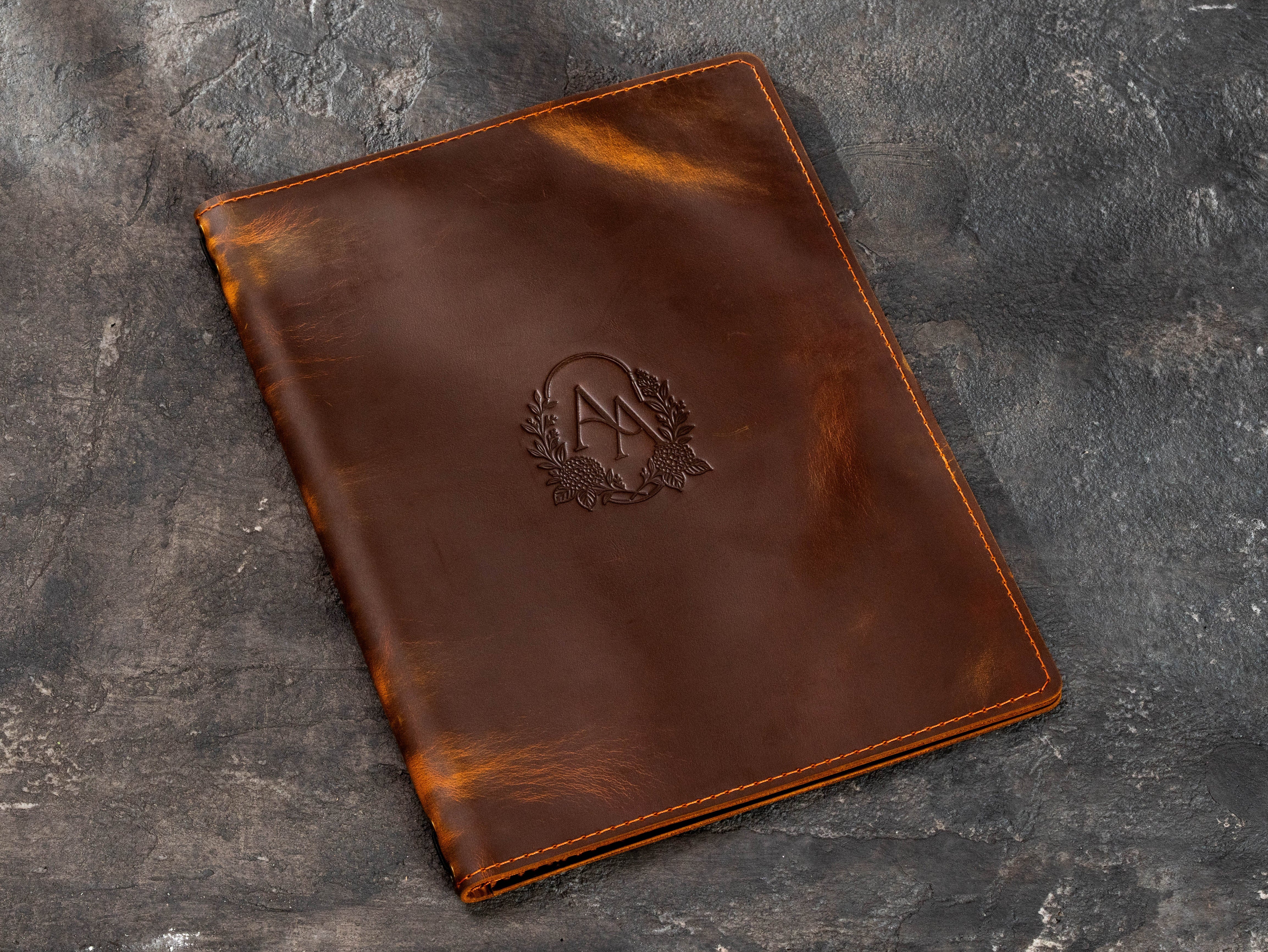 Large custom brown leather menu folder with floral monogram embossing and reinforced stitched border