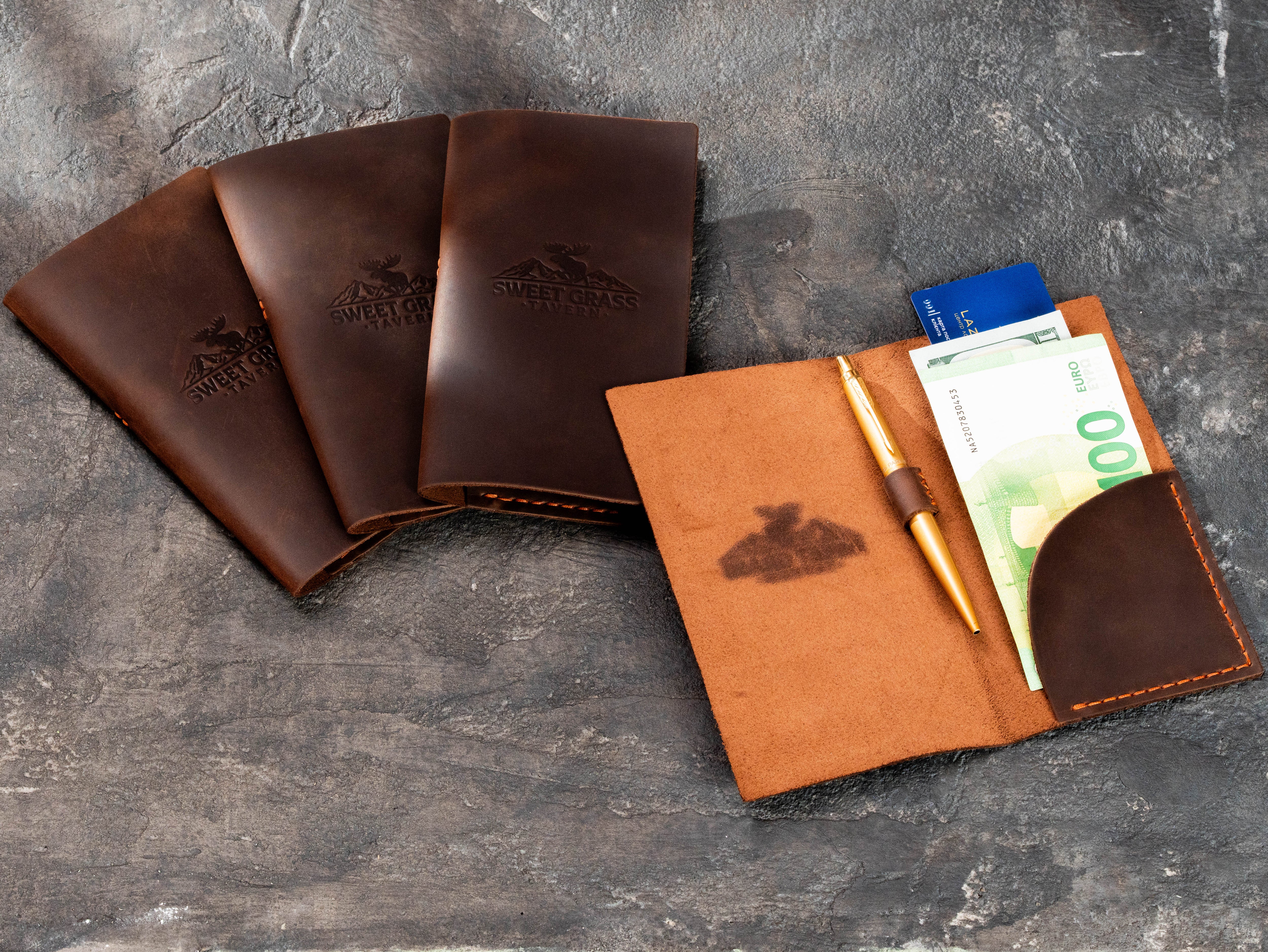 Brown leather check presenters with blind embossed Sweet Grass Tavern logo for a lodge-style restaurant
