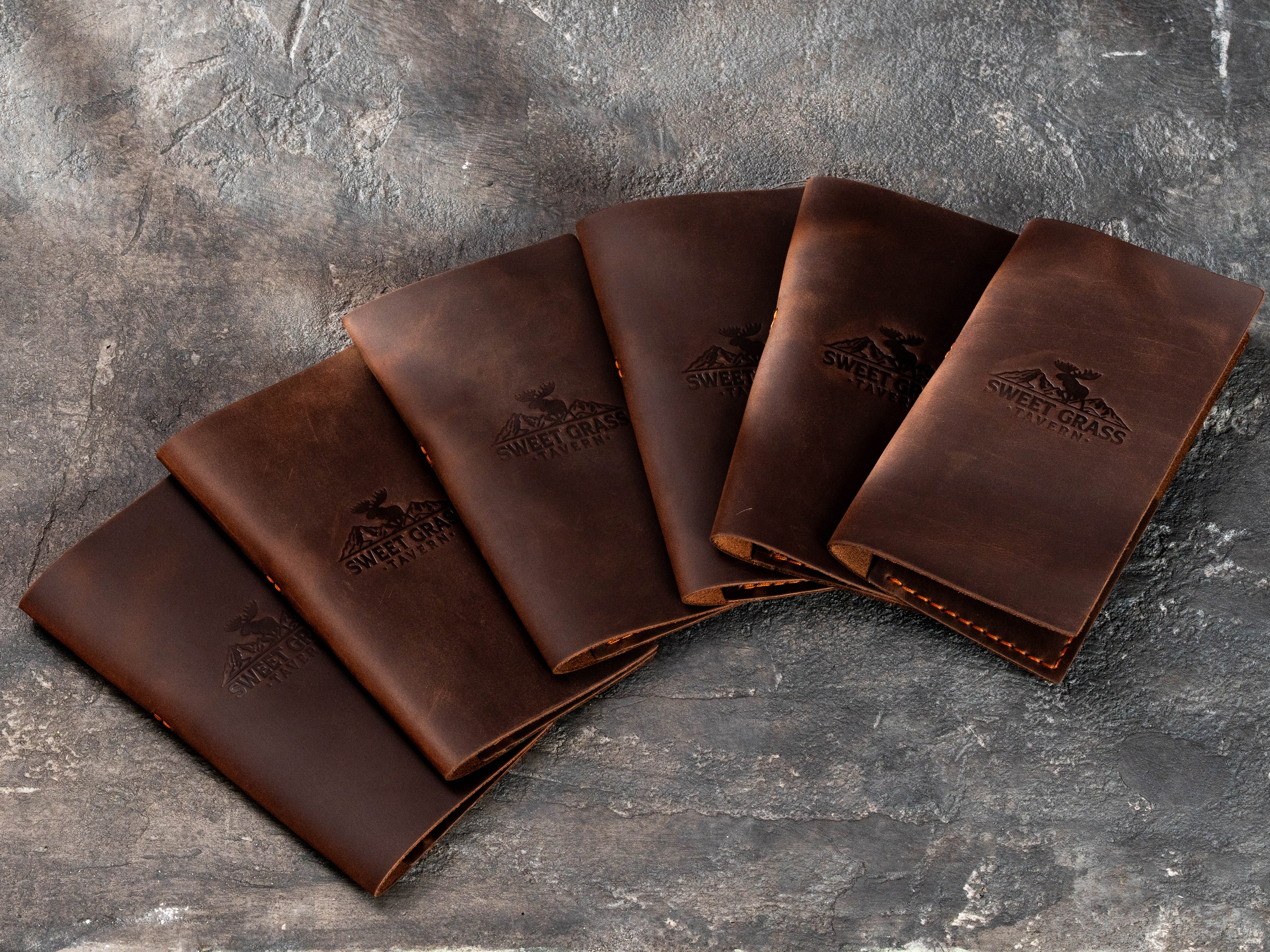Bulk custom leather check presenters in dark brown with embossed logo for tavern and lodge restaurant service