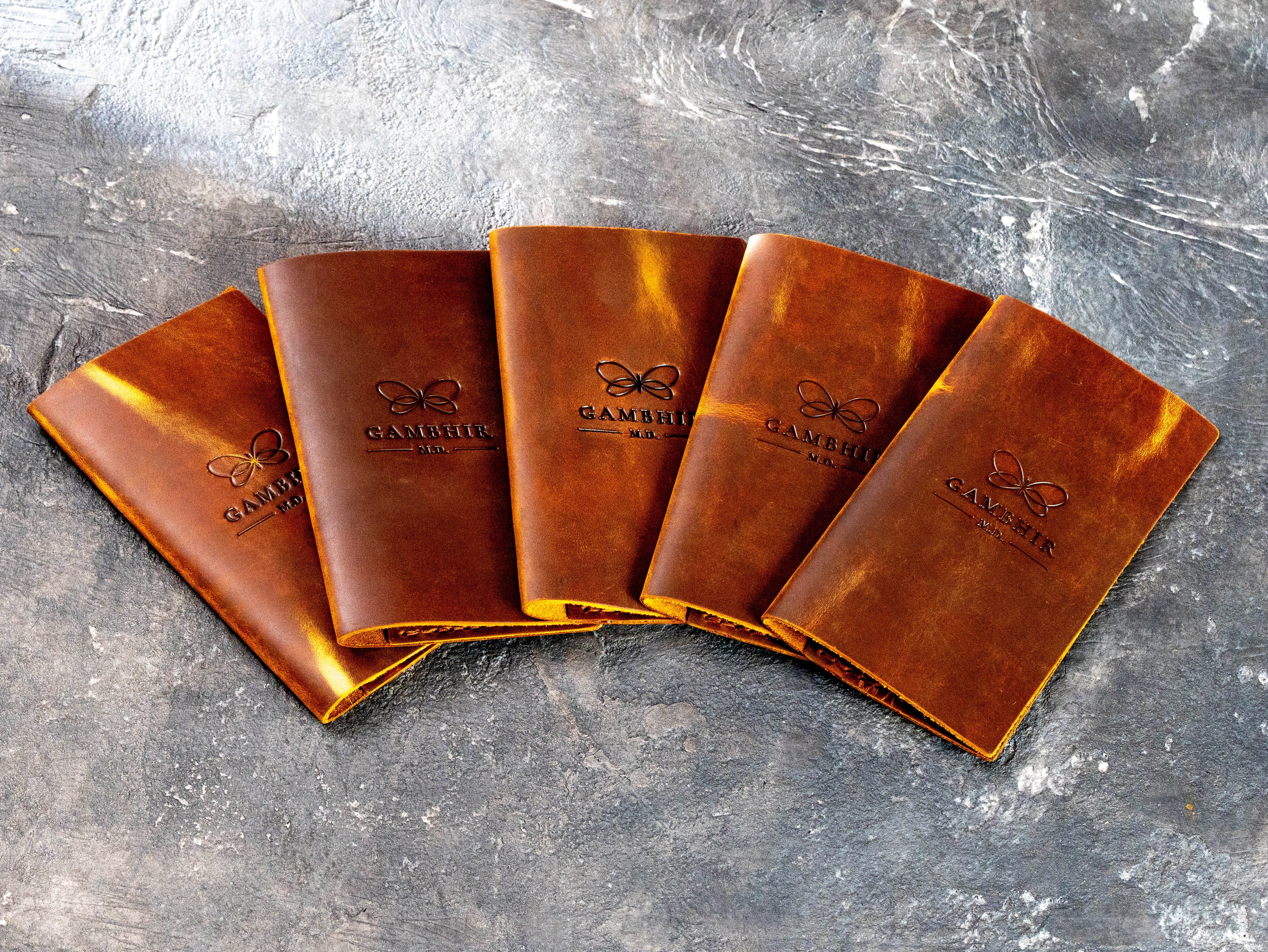 Set of vintage chestnut leather check presenters with blind embossed Gambhir M.D. logo