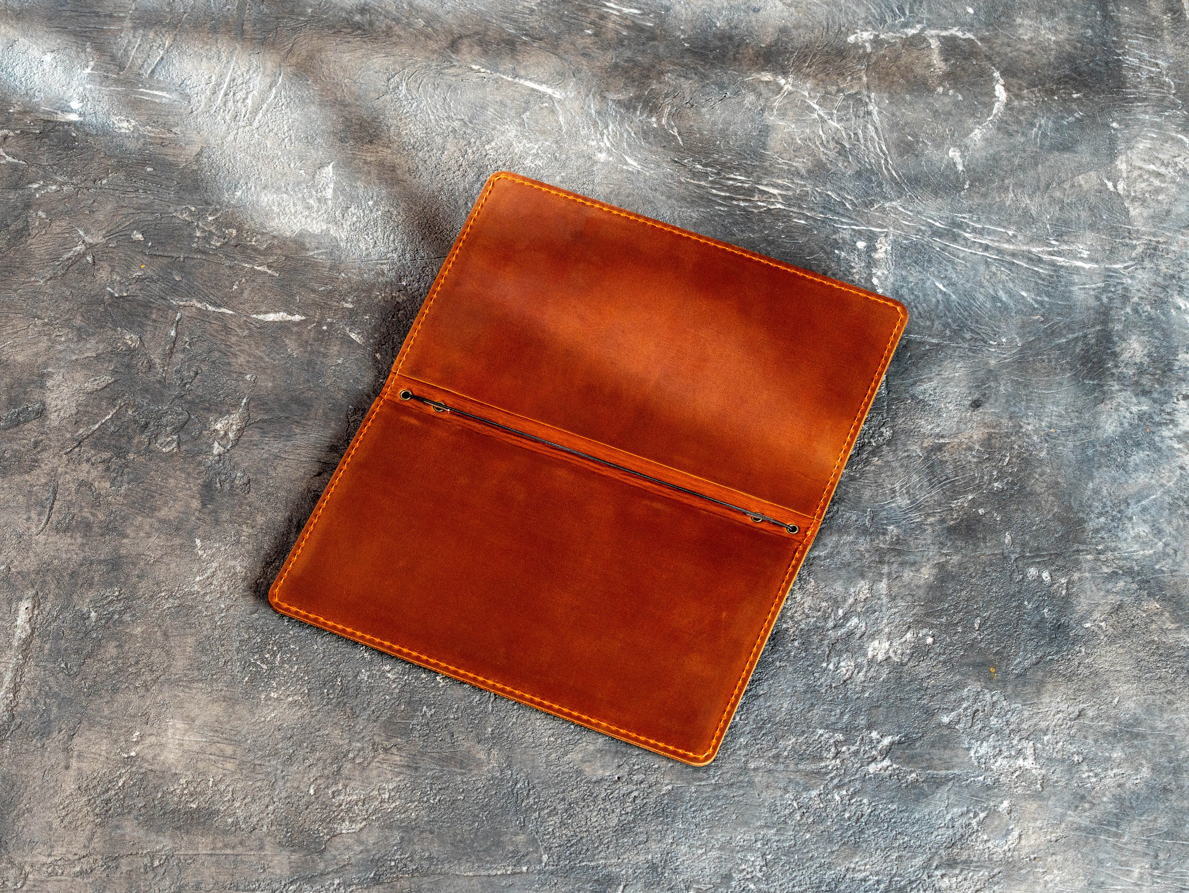 Angled view of an open chestnut leather menu folder with stitched double-layer construction