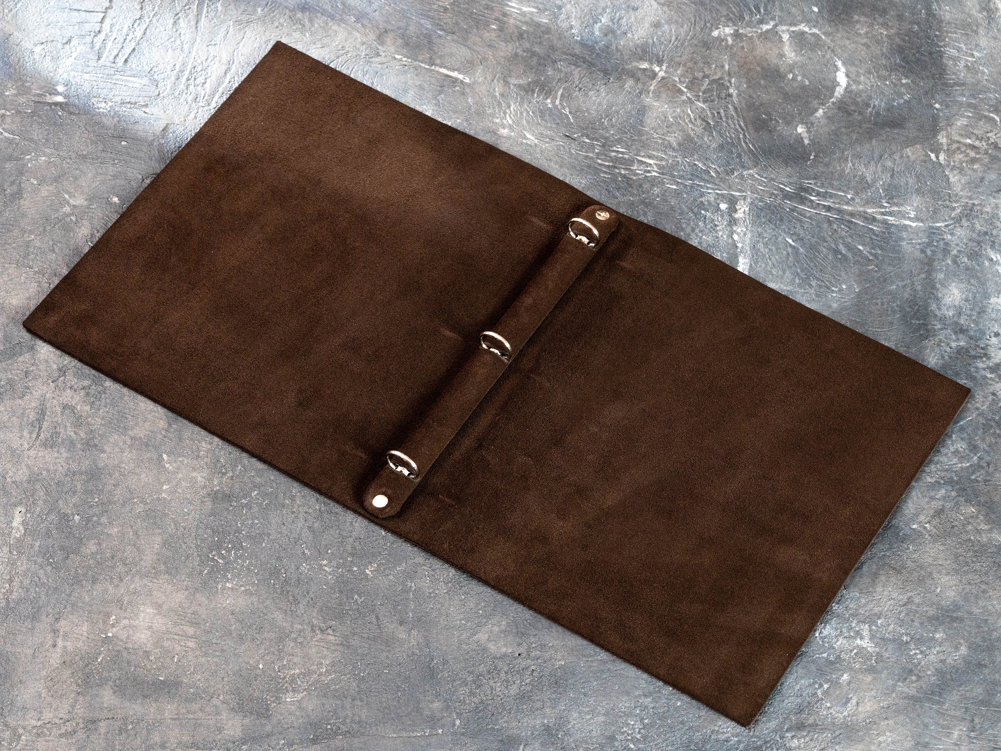 Interior view of a flexible leather binder with three round rings and natural suede lining