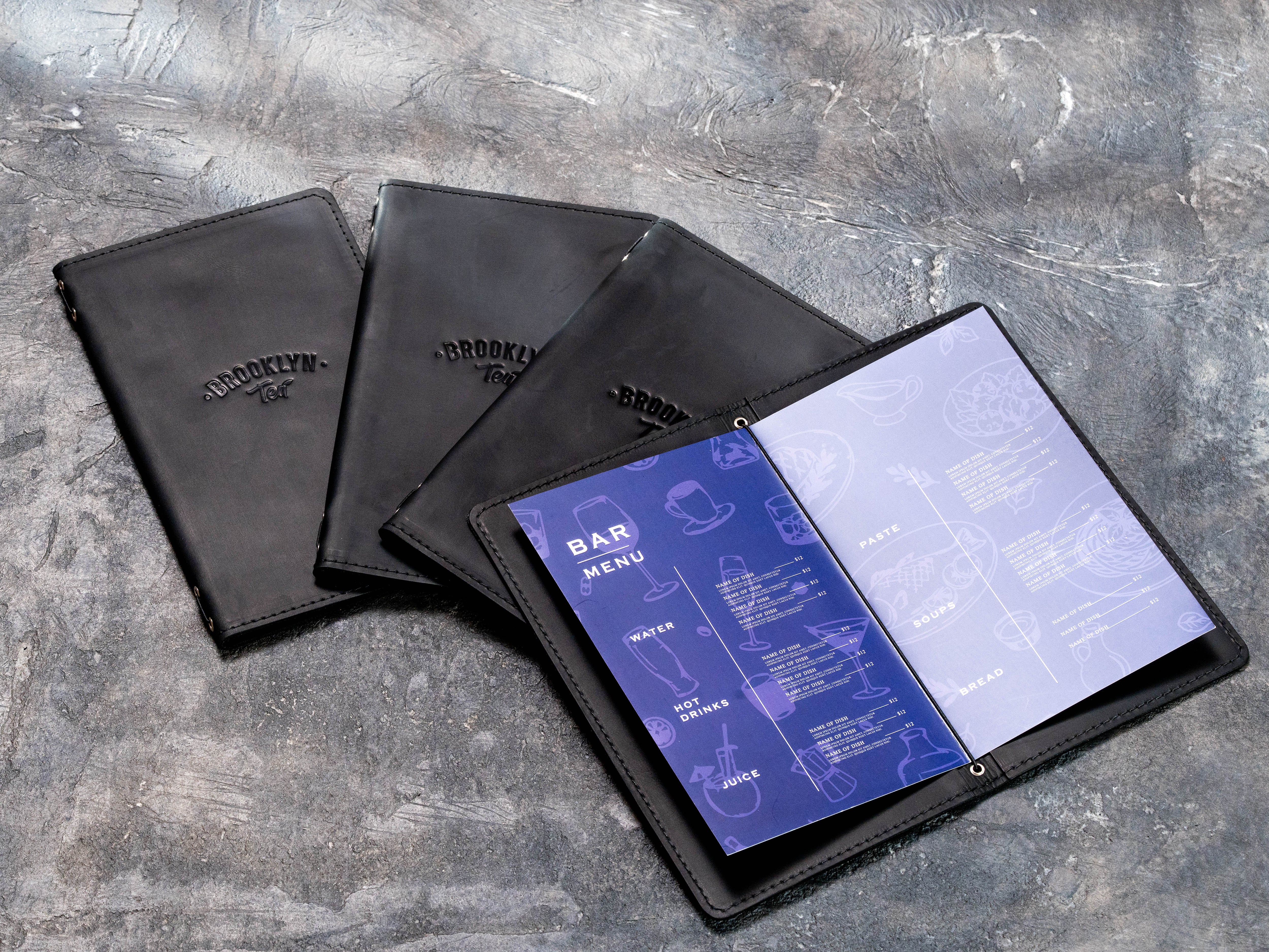 Set of custom black leather bar menu covers made by Mureli Workshop with blind embossed Brooklyn Tea logos