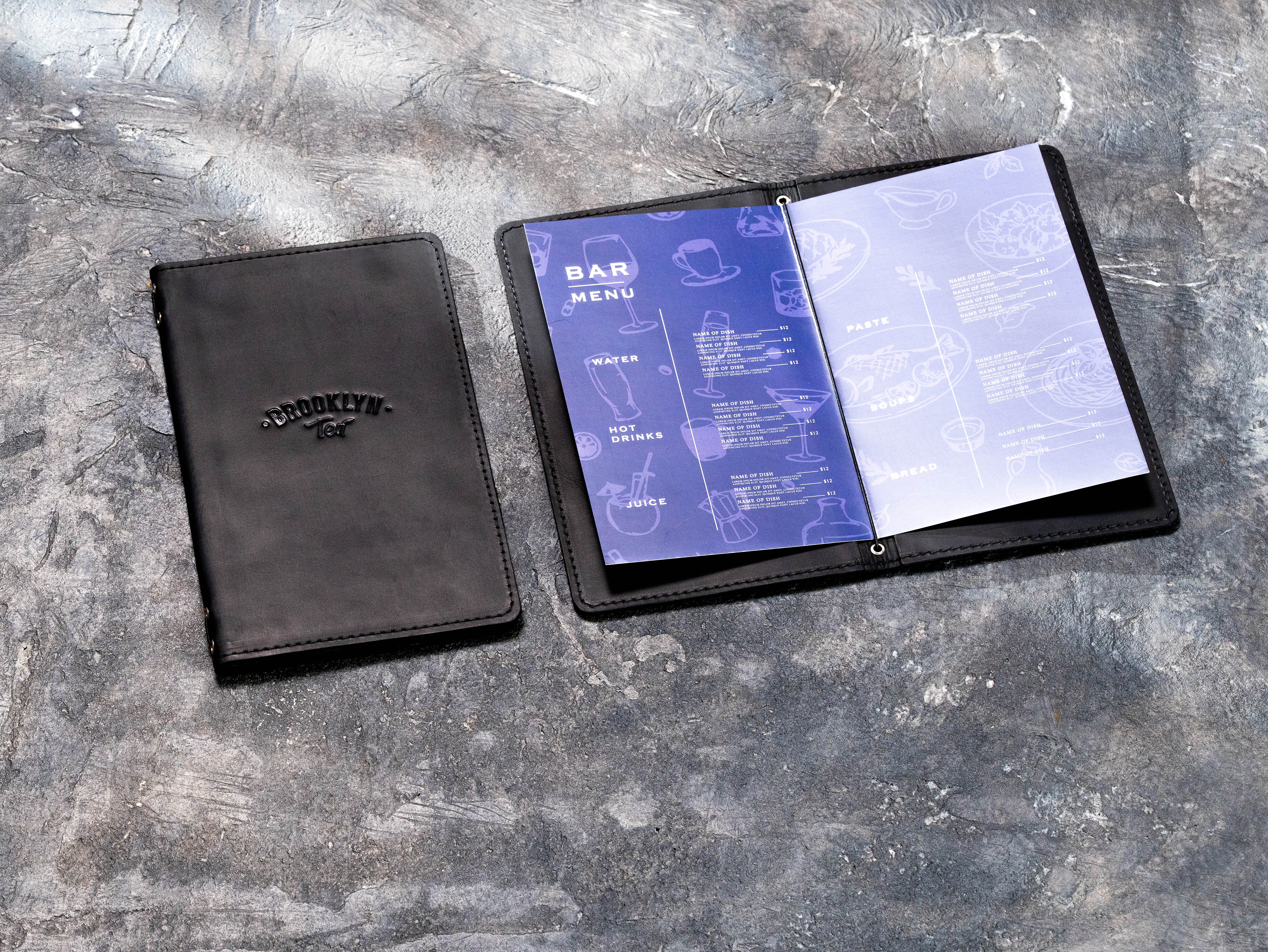 Open black leather bar menu cover with elastic binding shown beside a closed branded cover