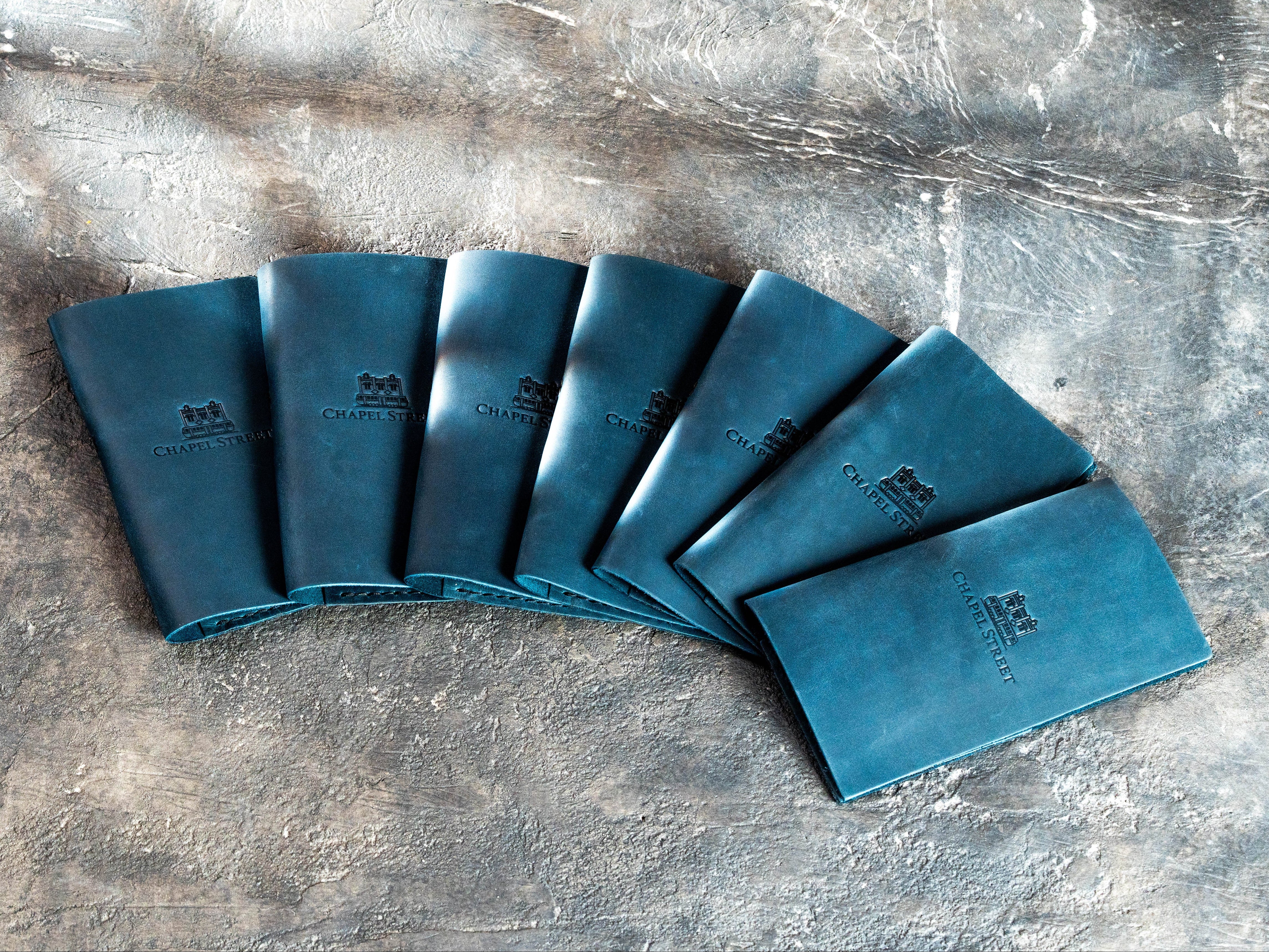 Set of custom blue Crazy Horse leather check presenters with blind embossed Chapel Street logos