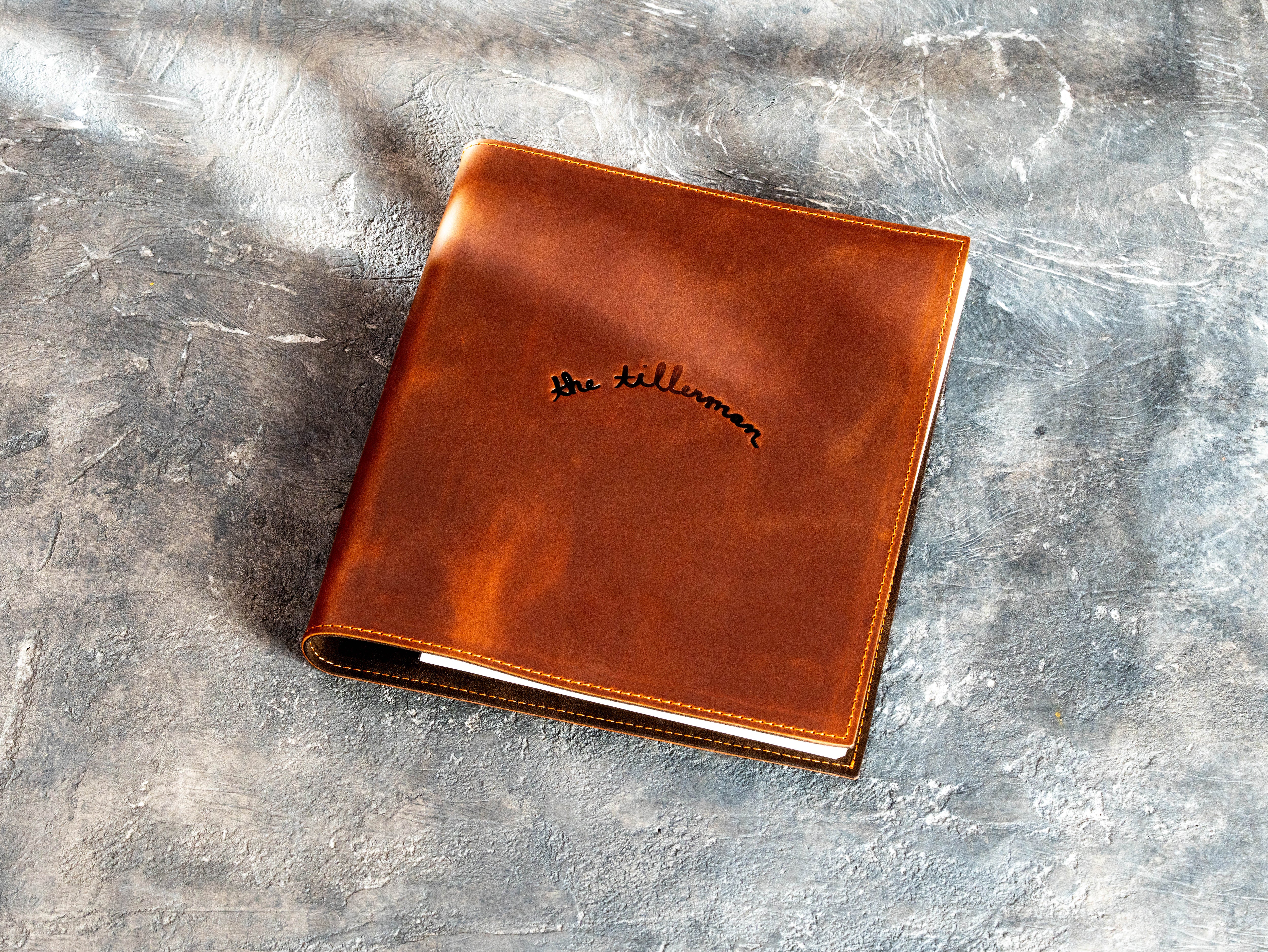 Closed copper Crazy Horse leather binder with custom The Tillerman logo and stitched edges