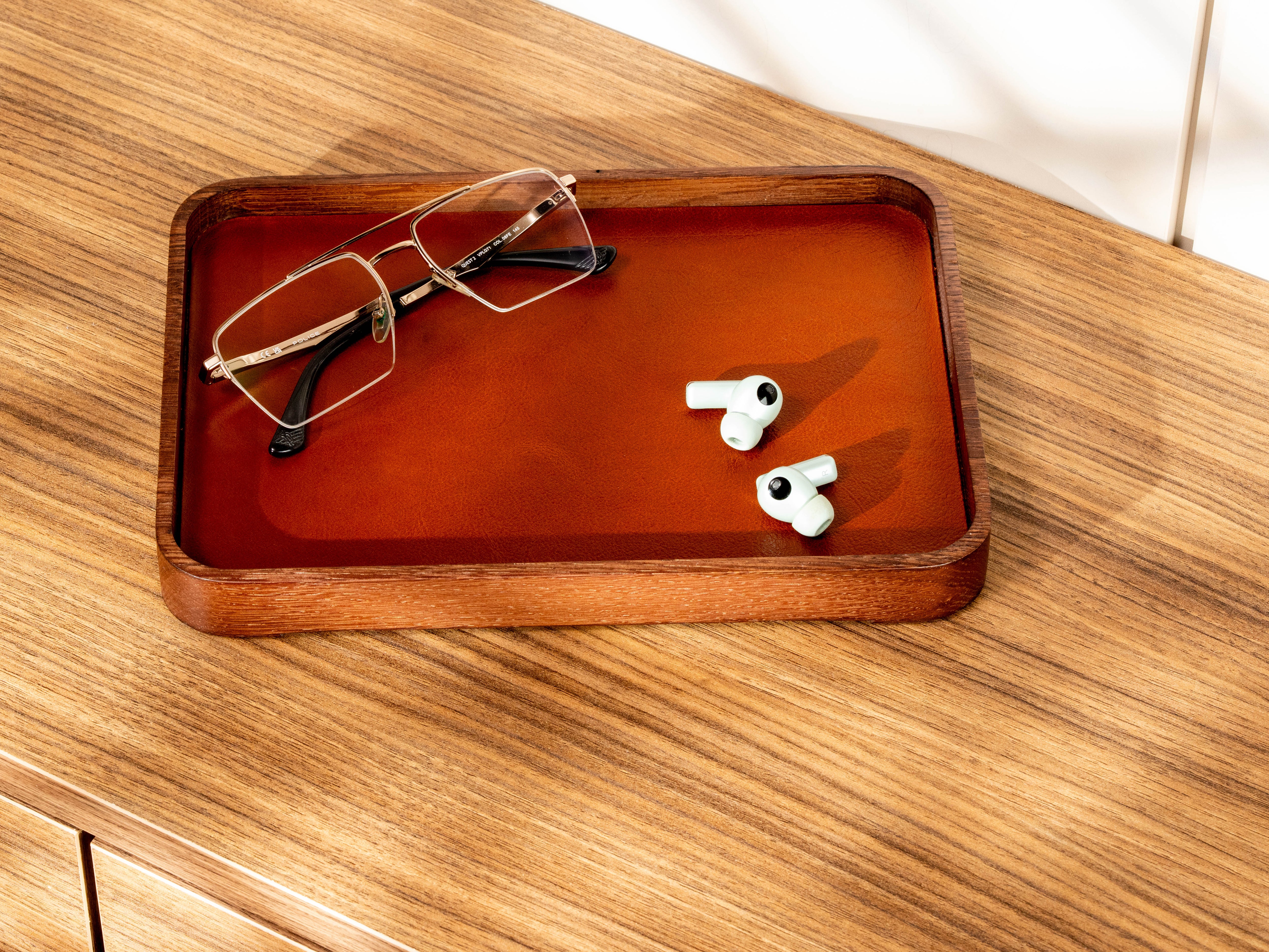 Oak wood and Camel leather nightstand organizer holding eyeglasses and wireless earbuds.