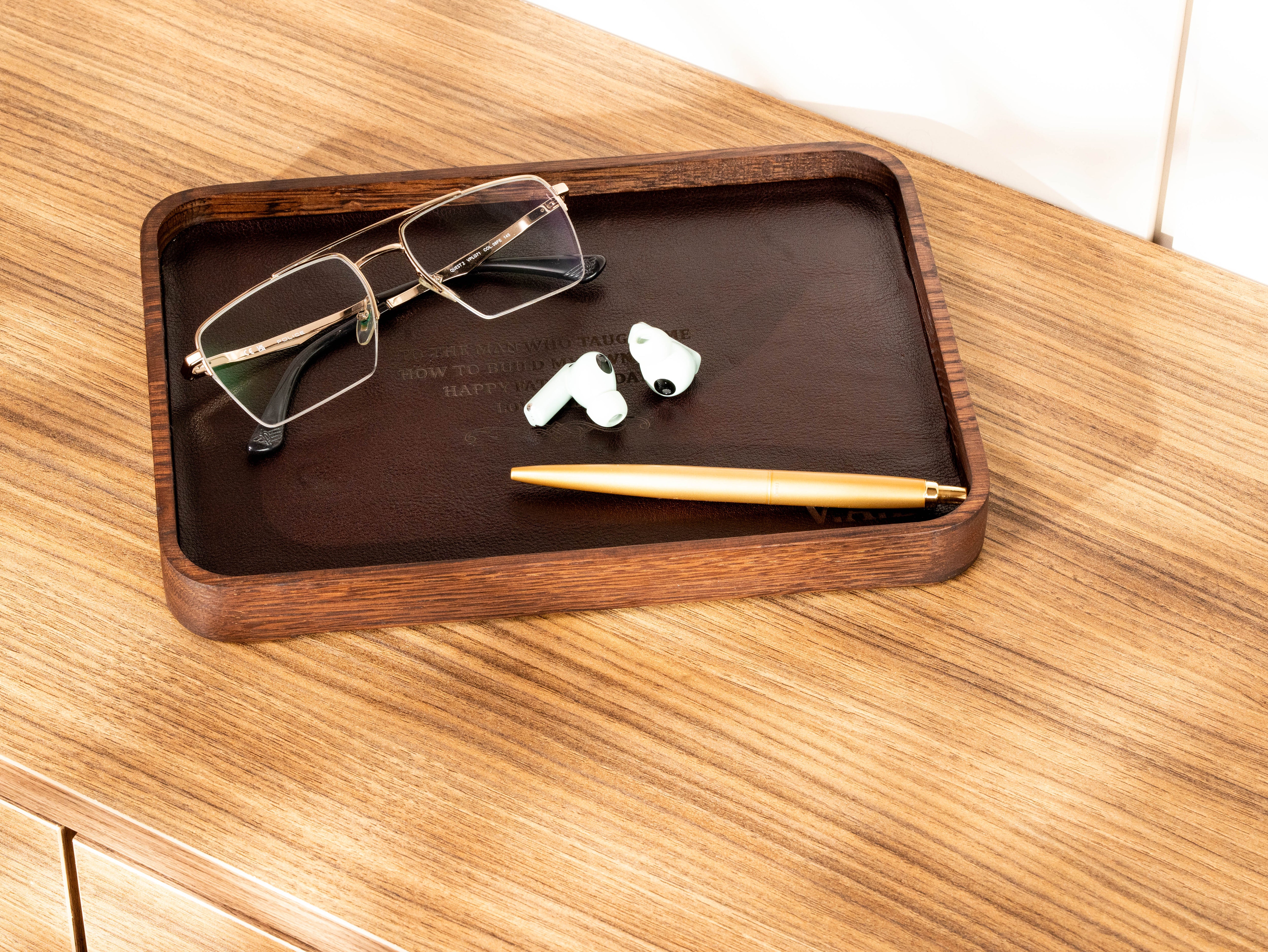 Personalized dark oak wood valet tray with dark brown leather, glasses, earbuds and pen for desk or nightstand organization.