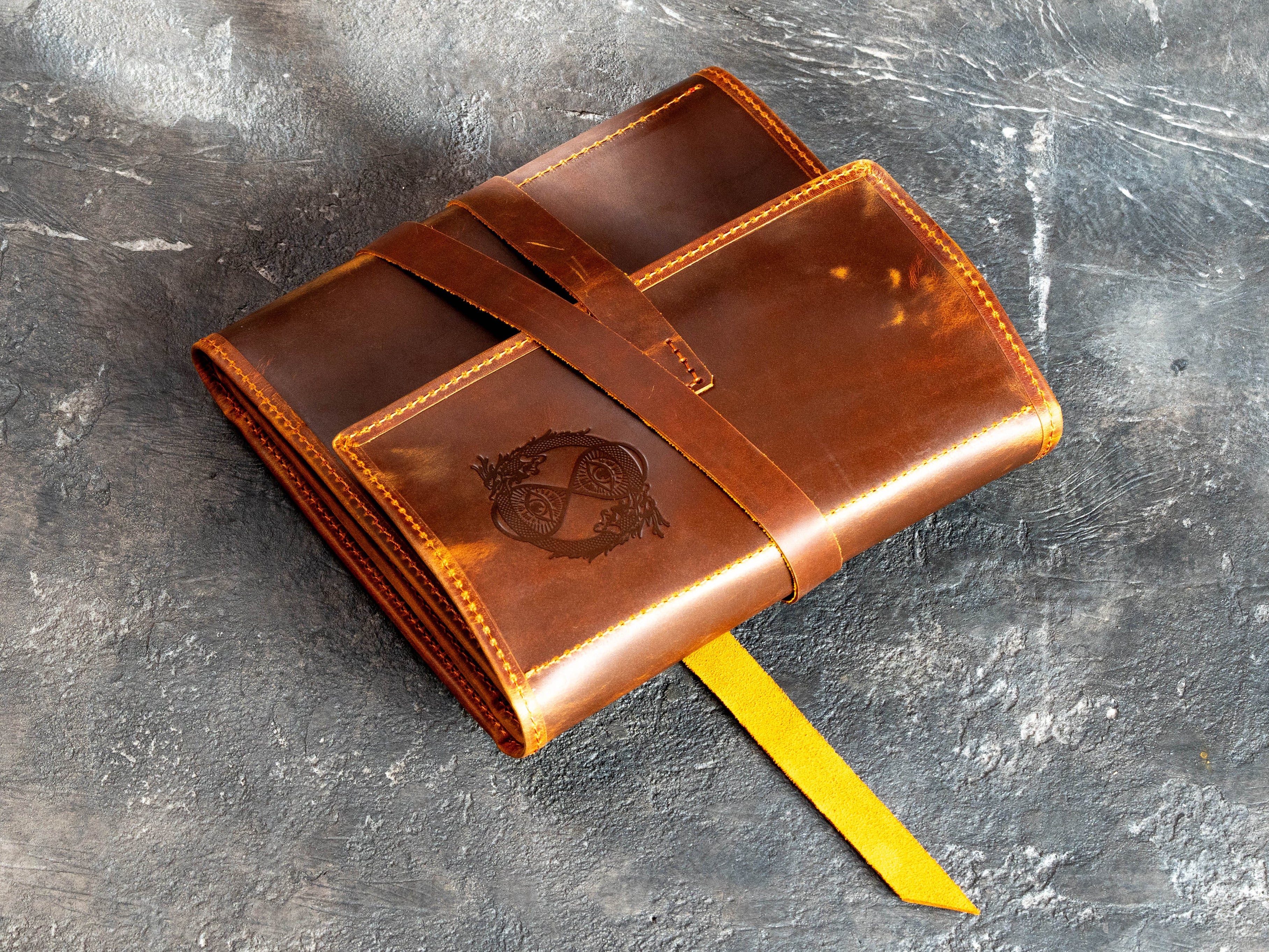 Folded personalized brown Crazy Horse leather artist organizer with wrap closure and custom owl embossing